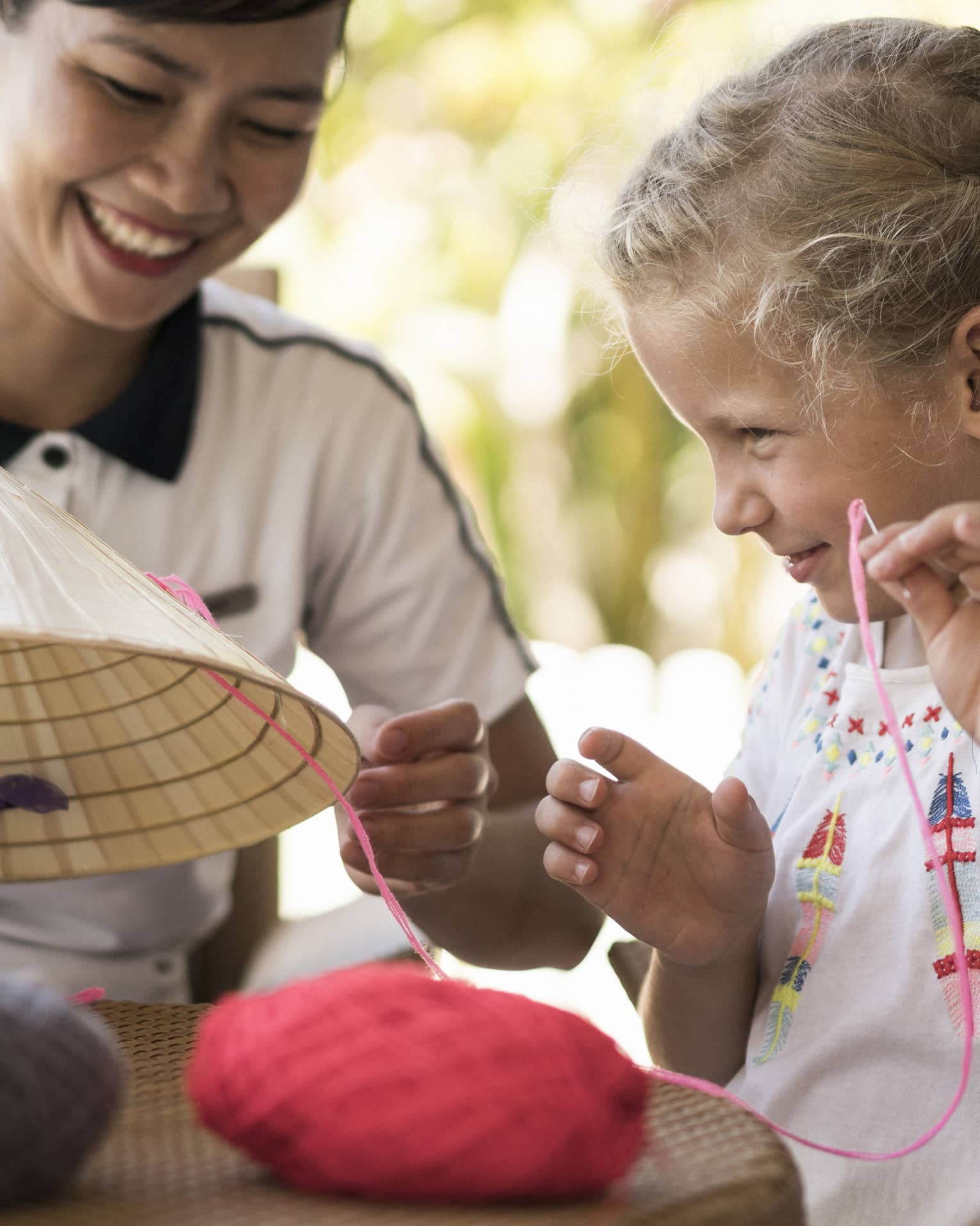 Hotel staff helps young girl thread string on traditional hat