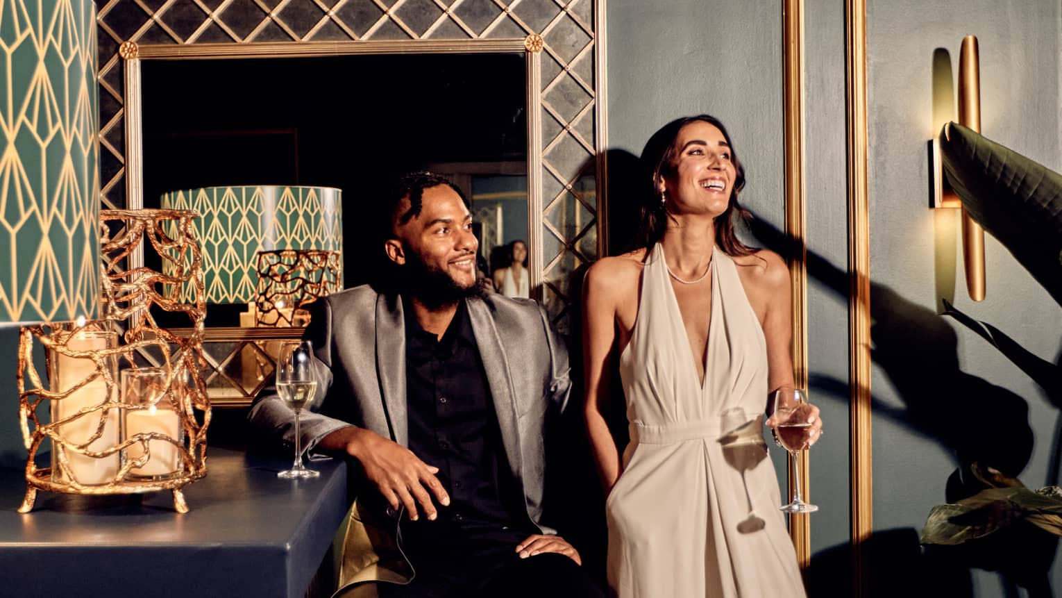 A man and woman leaning on a green wall with gold accents.