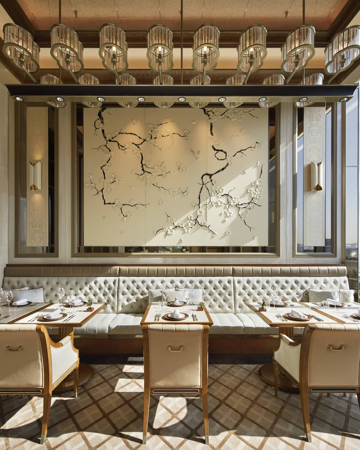 Est dining room with tables for two, muted cream decor, natural light, view of the city 