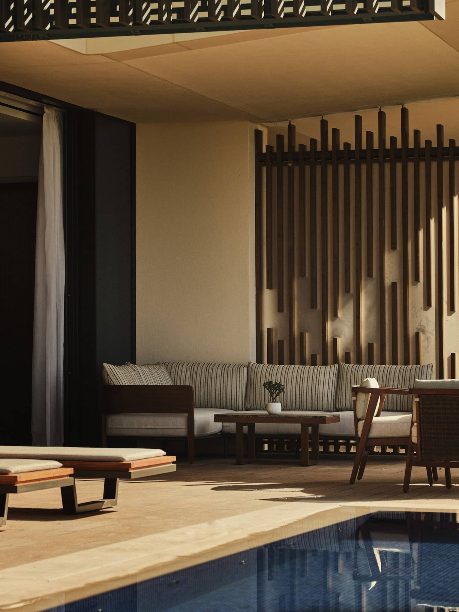 Contemporary pool terrace of a luxury suite at tropical resort, featuring sun loungers and a dining table