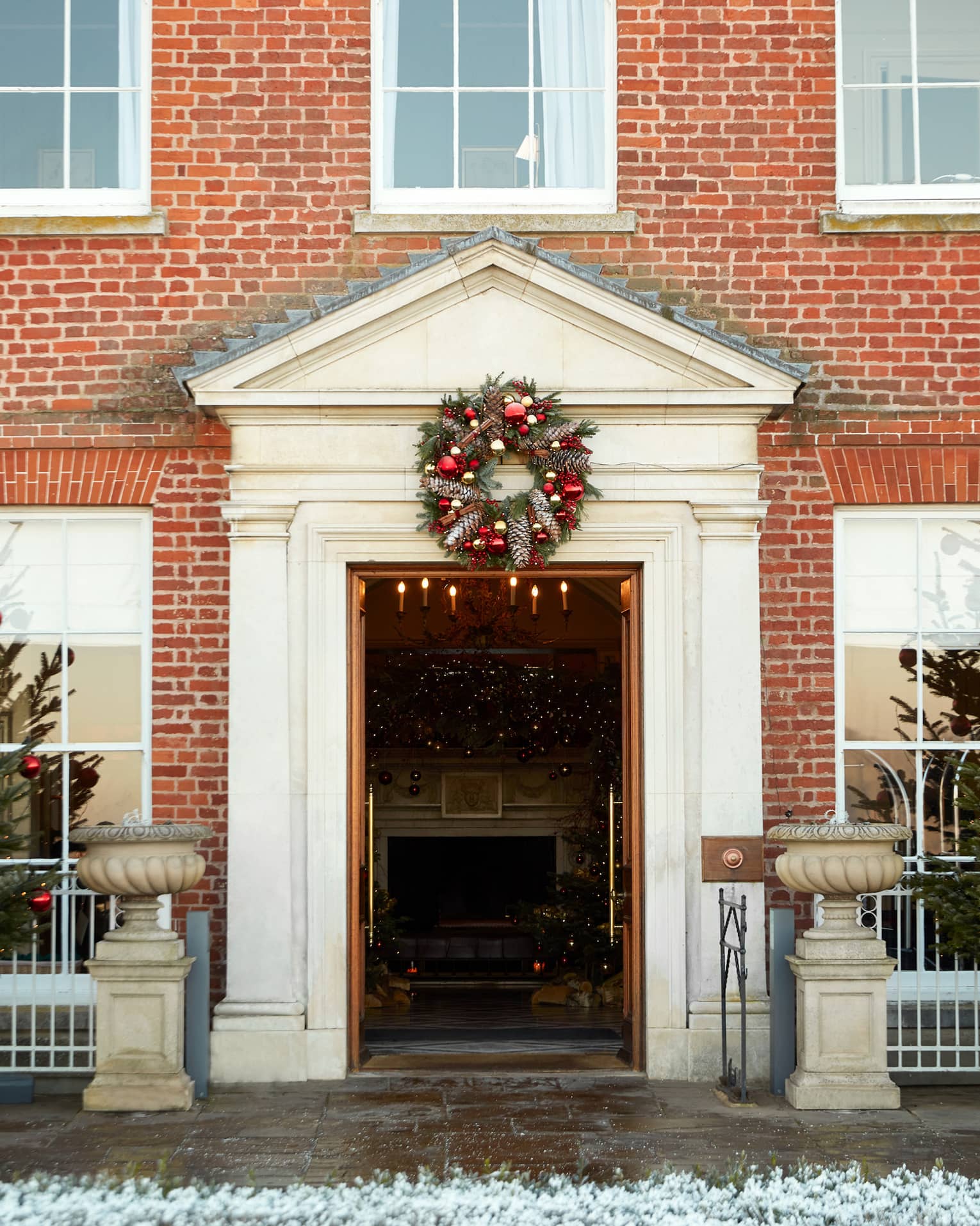 Stately red brick hotel exterior with holiday wreath over door flanked by Christmas trees