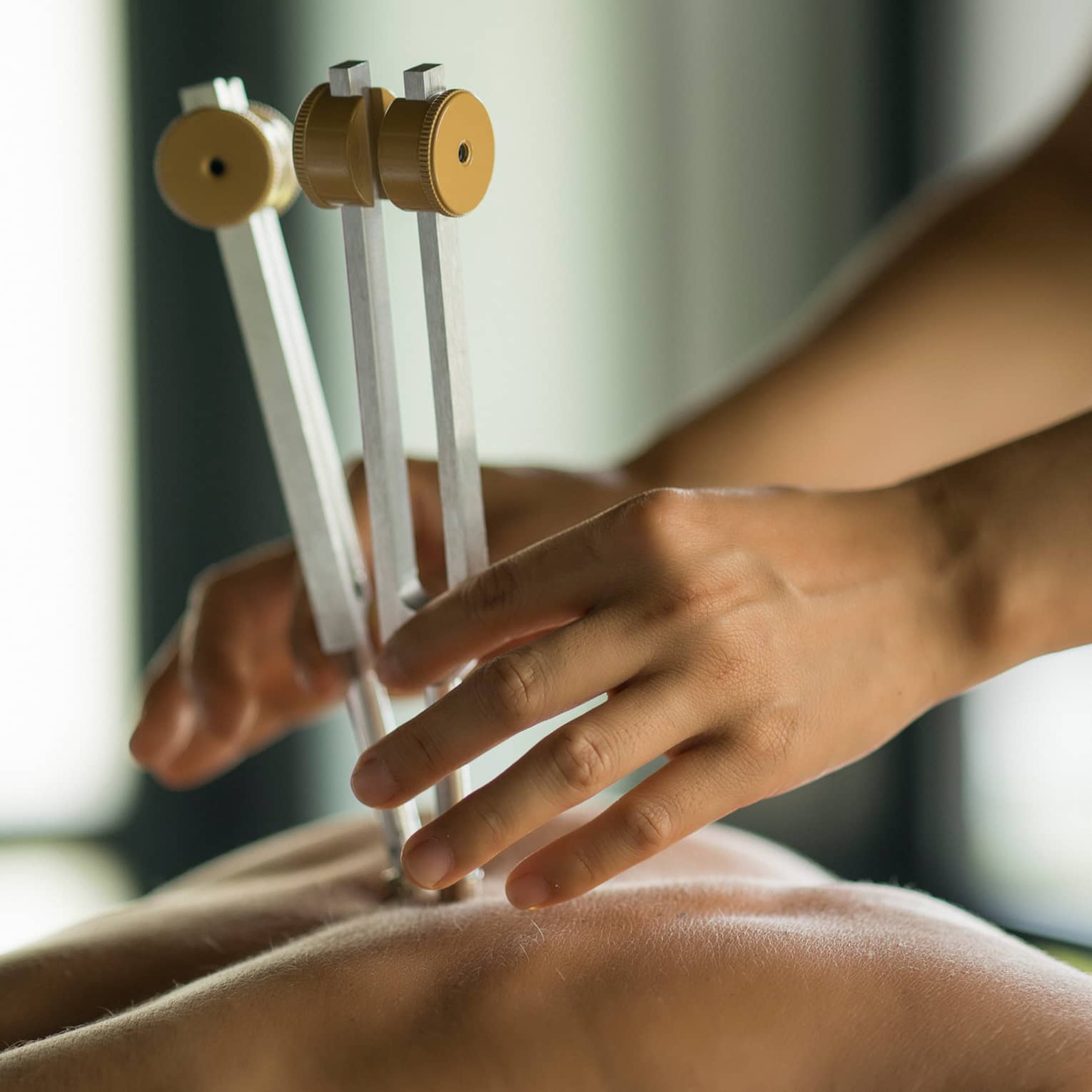 Masseuse uses wood tool on woman's spine, bare back in spa