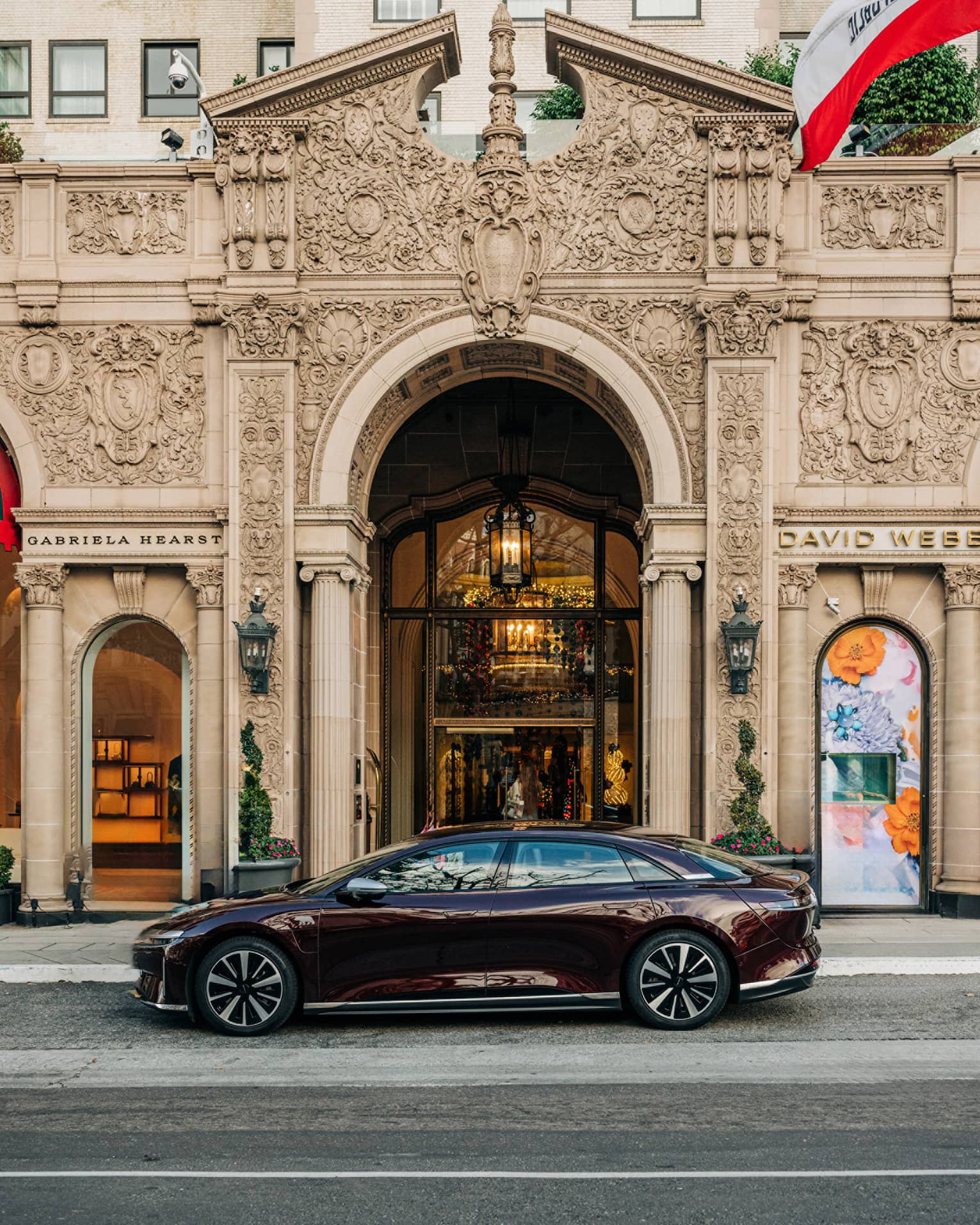 A hotel car parked outside of a building with arched doorways and flags