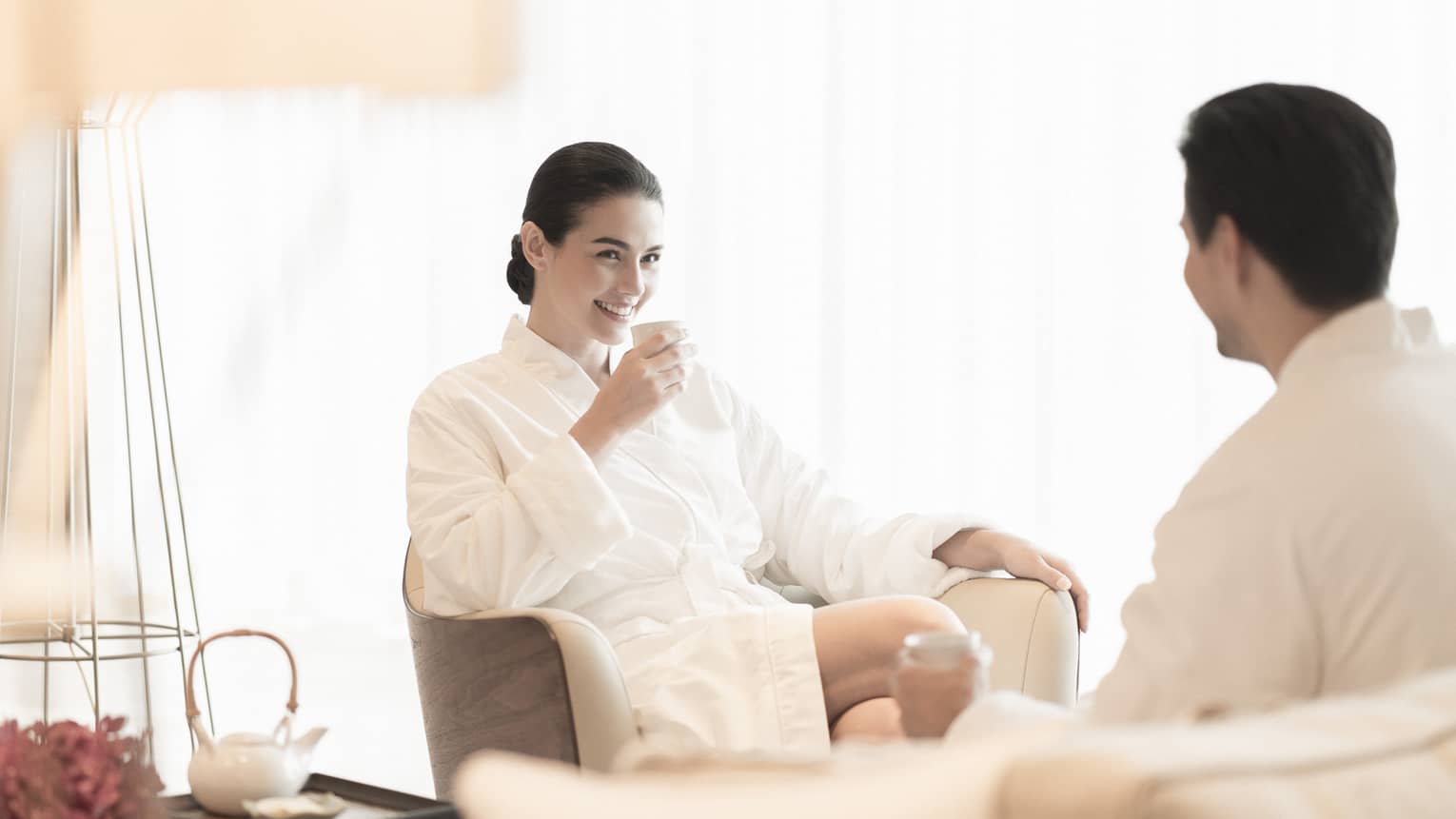 Couple wearing white robes relax in spa lounge 