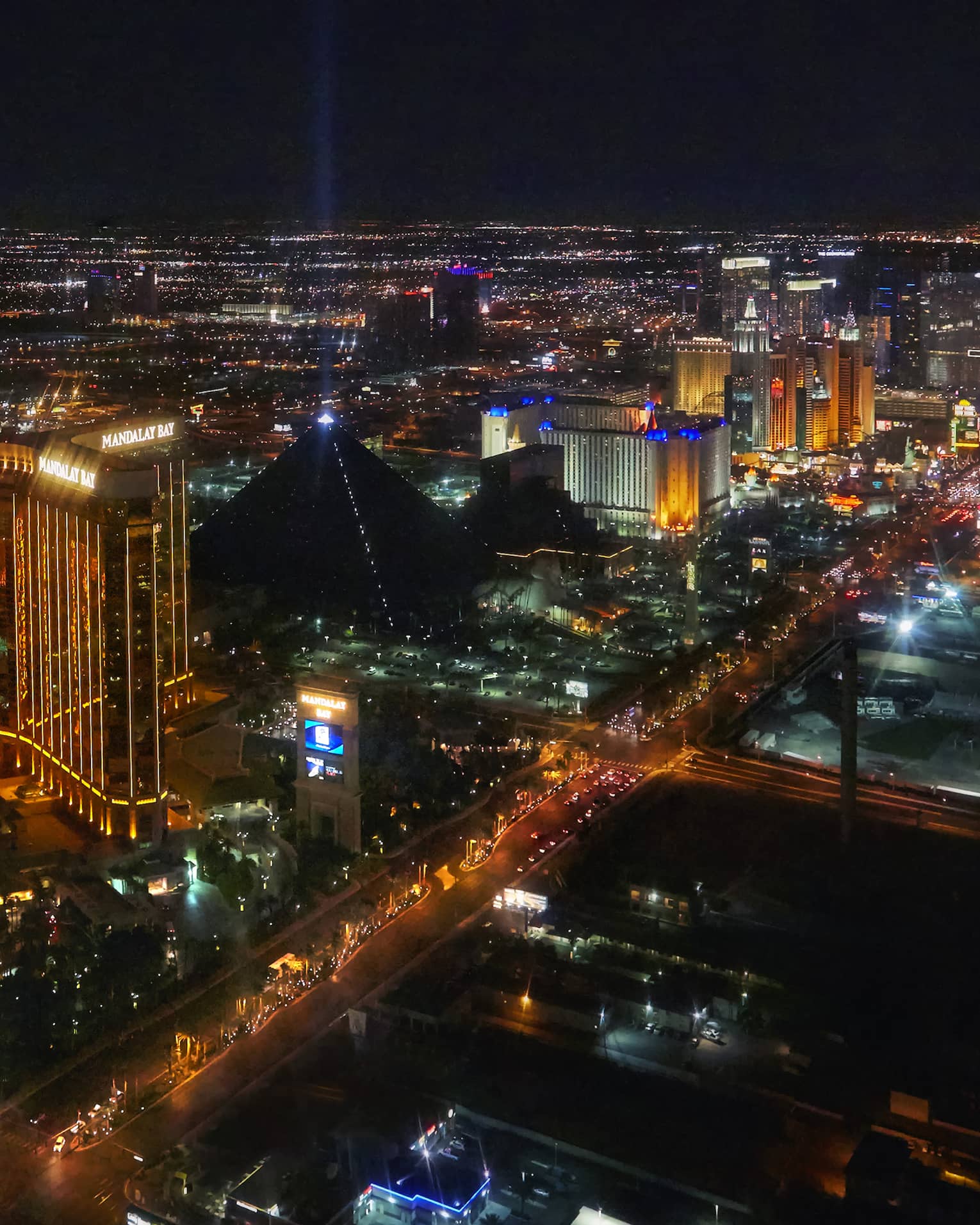 A bird's-eye view of the Las Vegas skyline at night, multicoloured lights illuminating casinos lining Las Vegas Boulevard.