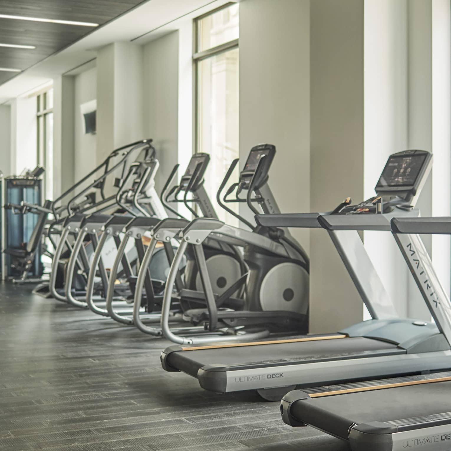 Treadmills, cardio machines in row by windows in Fitness Centre