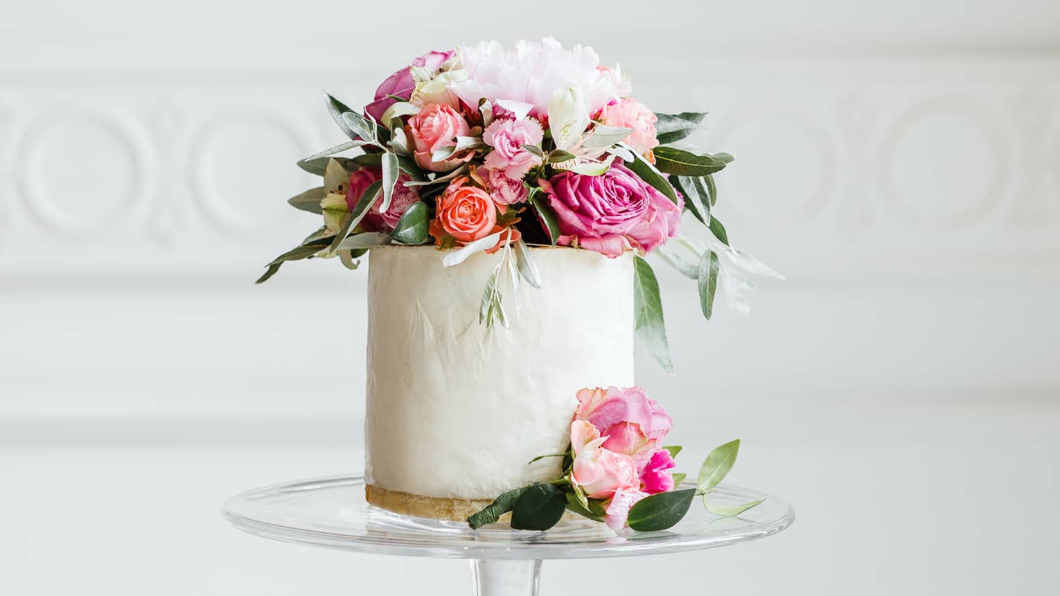 Elegant small white wedding cake topped with fresh pink and white roses 