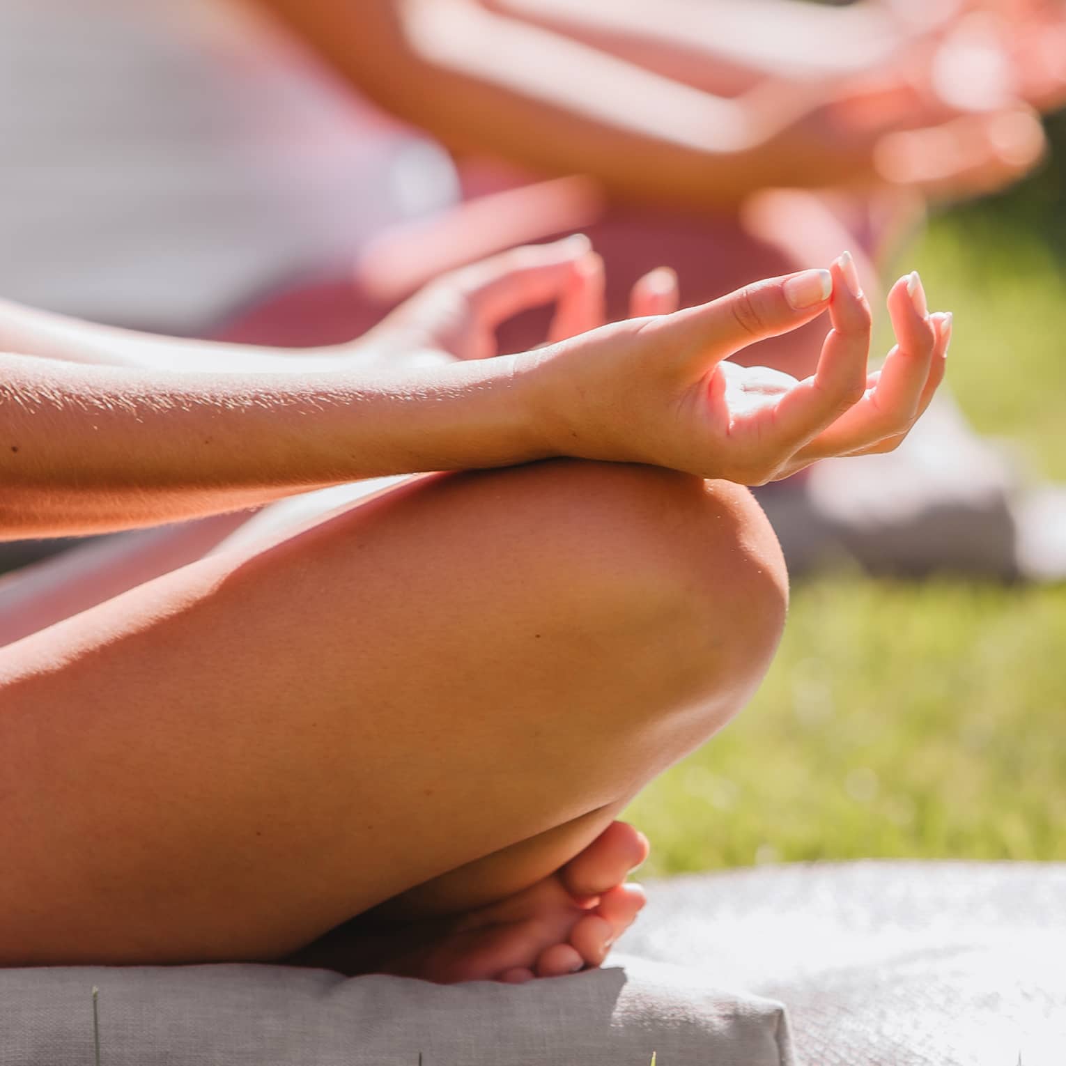 A group doing yoga outside with mats and towels.
