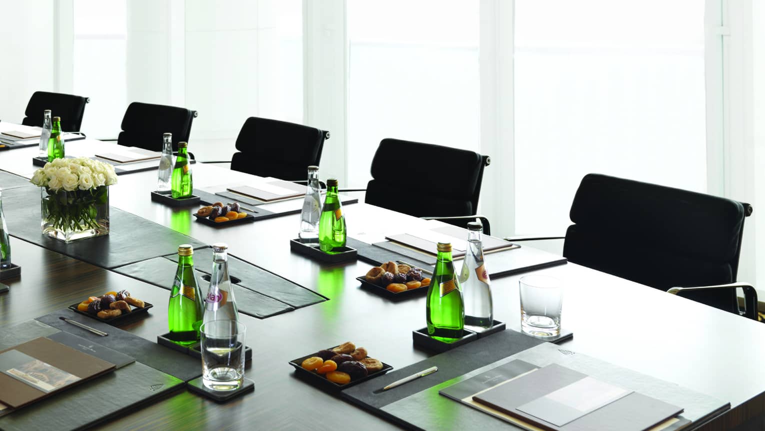Boardroom meeting table set with water, dried apricots, menus by sunny window