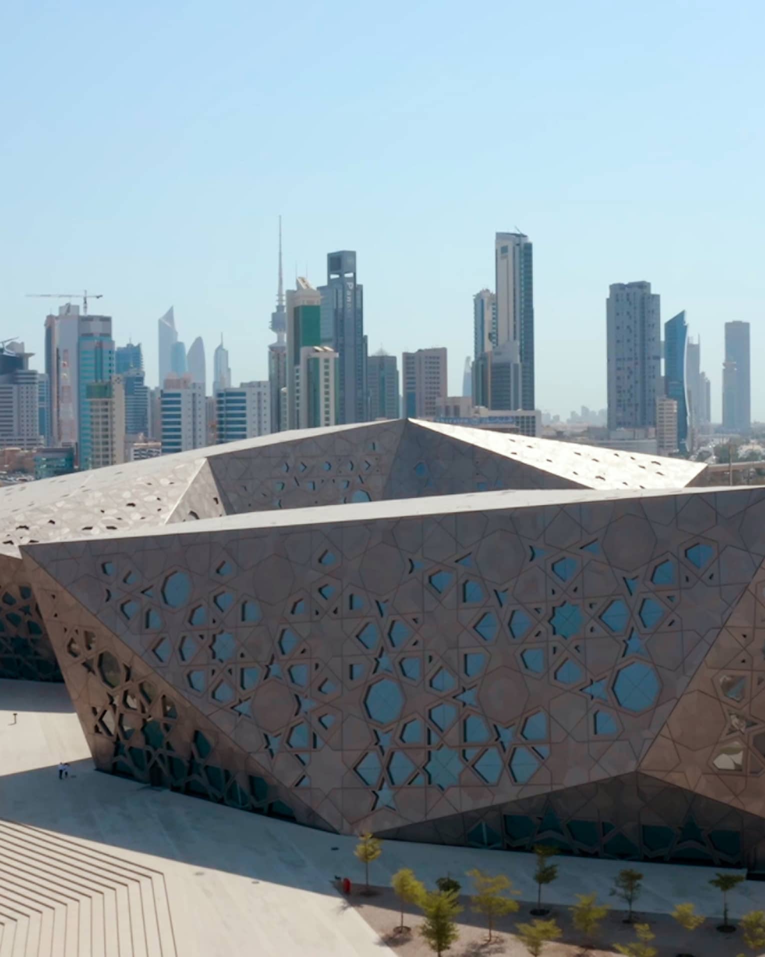 Metal-and-glass angluglar building with the Kuwait skyline in the background