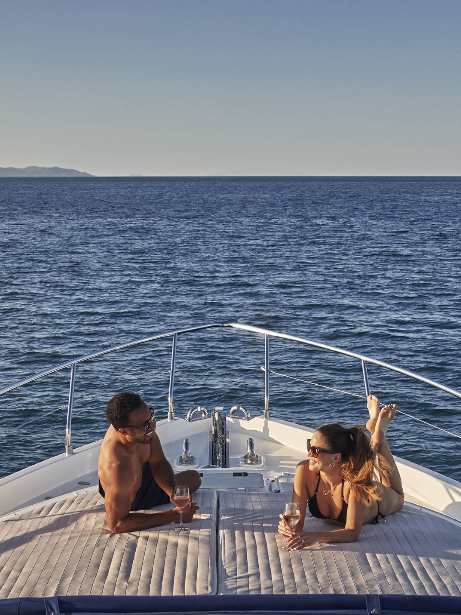 Man and woman lay on front of yacht