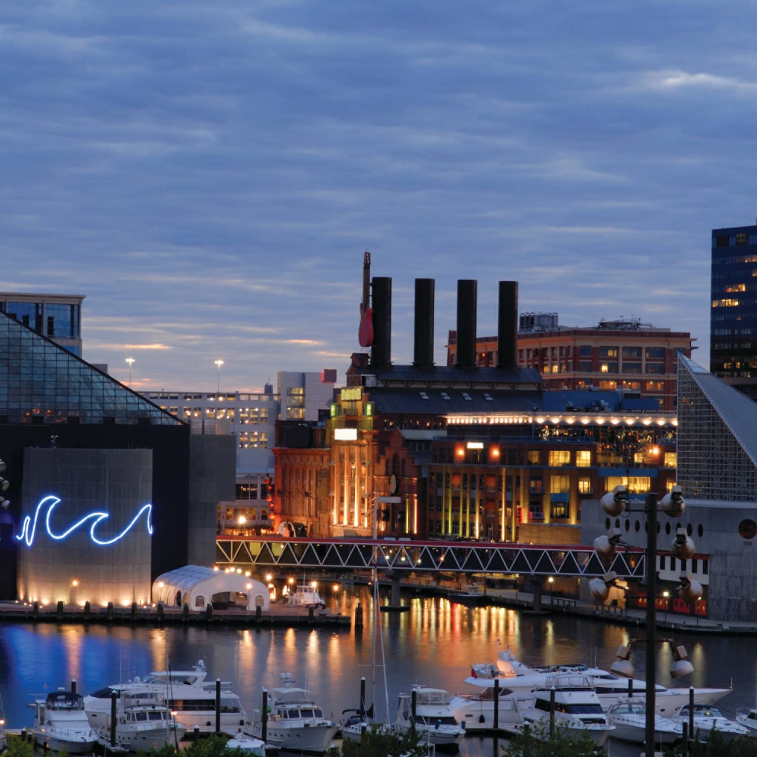 Baltimore buildings with fluorescent wave lights, boats in harbour at dusk