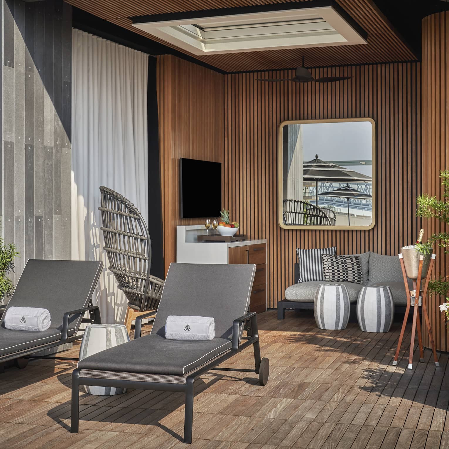 A cabana with two lounge chairs a sofa and plants.
