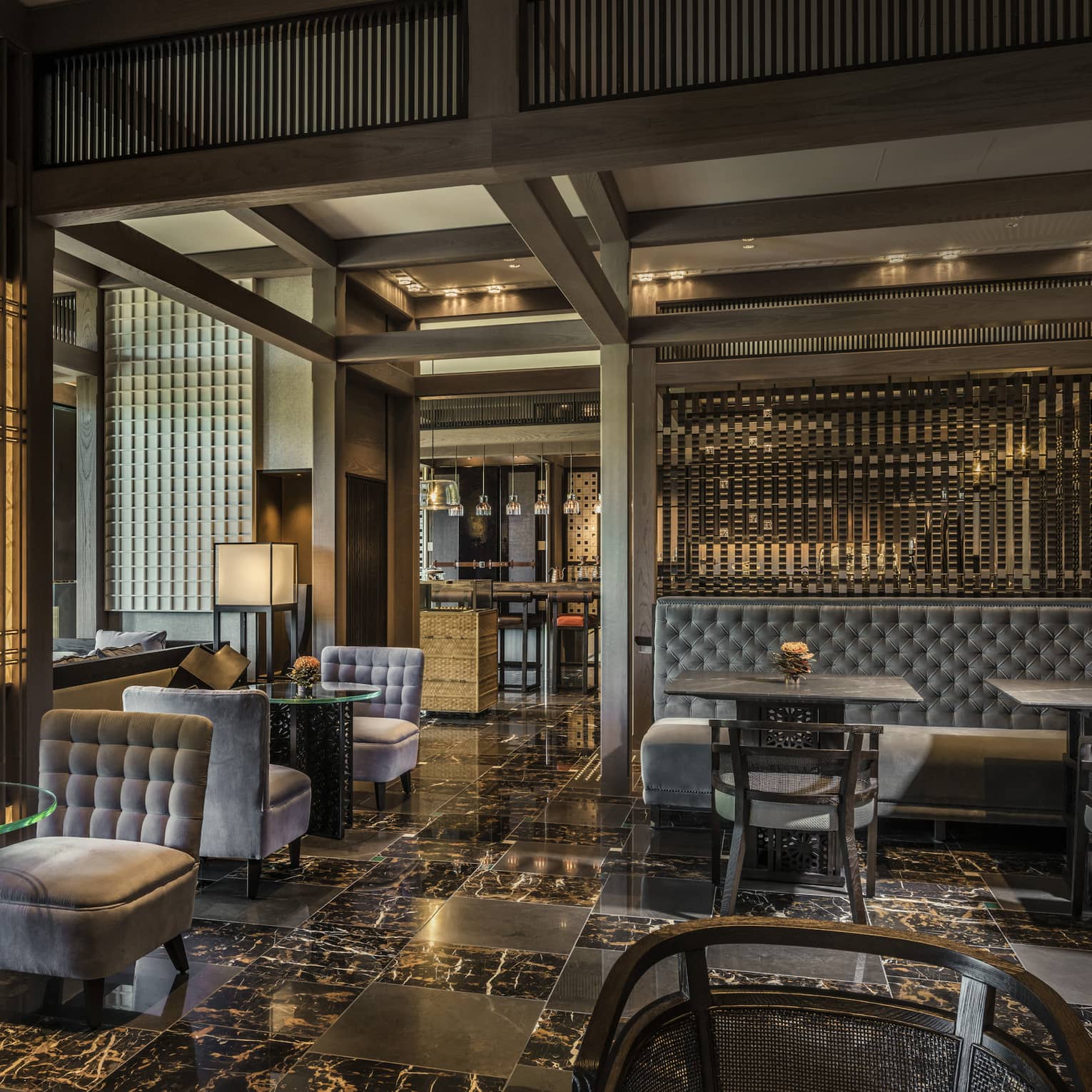 Plush grey velvet sofas, chairs on black marble floors in The Lounge dining room