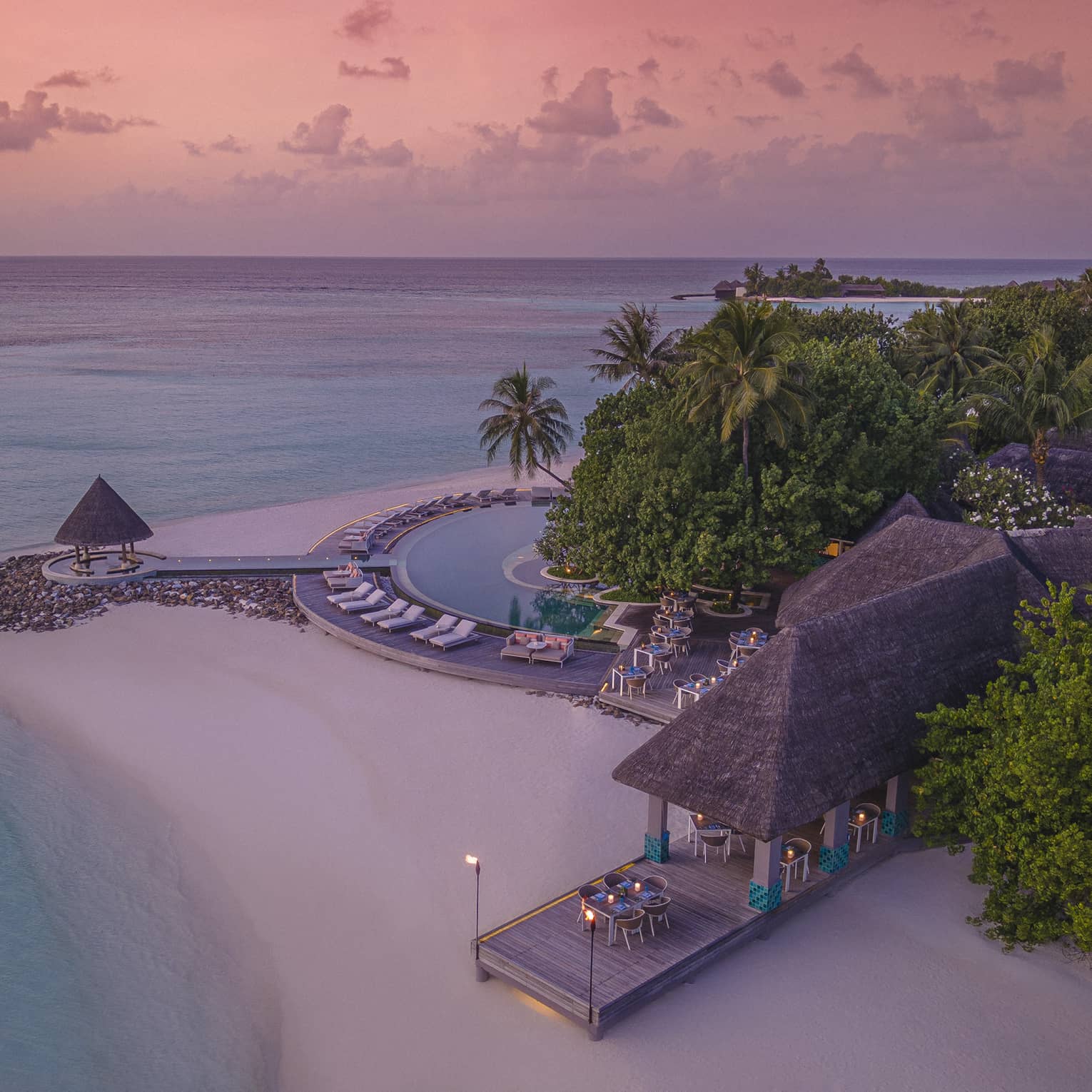 Aerial view of beachfront straw roof pavilion at sunset