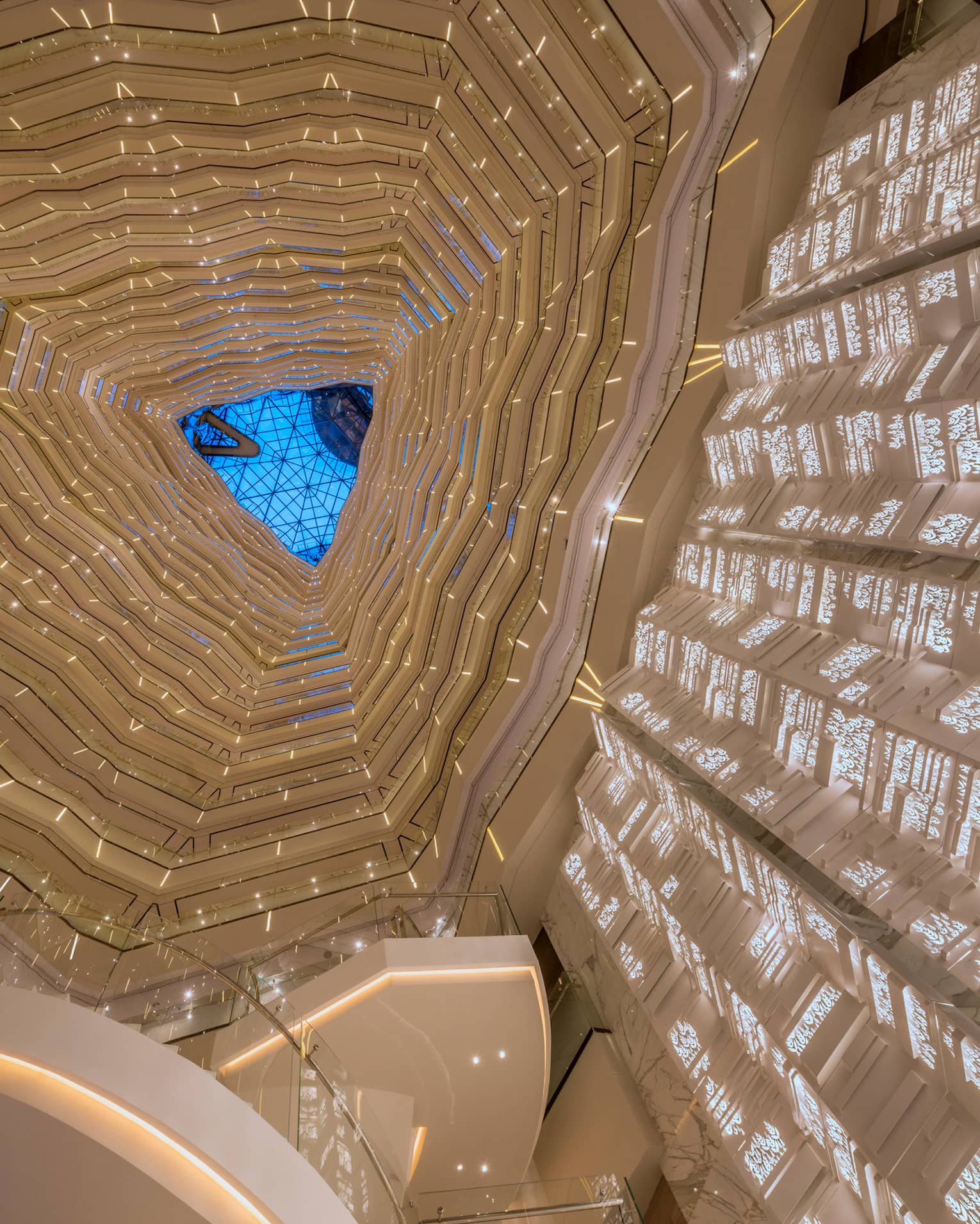 Triangular skylight seen past many floors of curved white balconies inside Four Seasons Hotel Guangzhou 