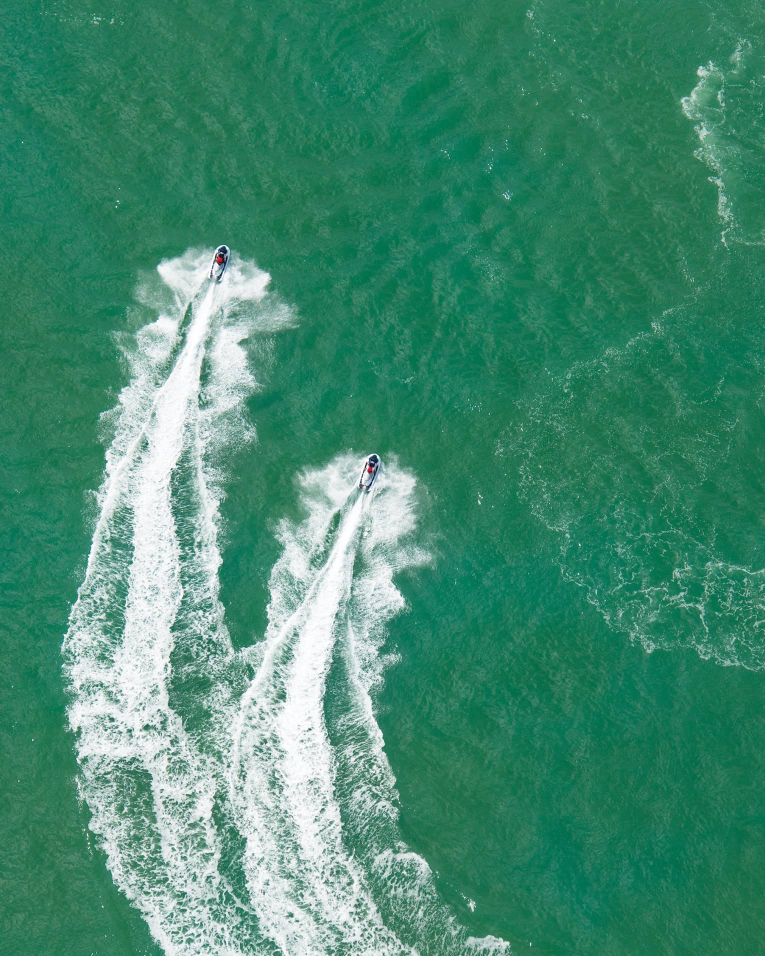 Aerial view of two jet skis, trails on water in ocean