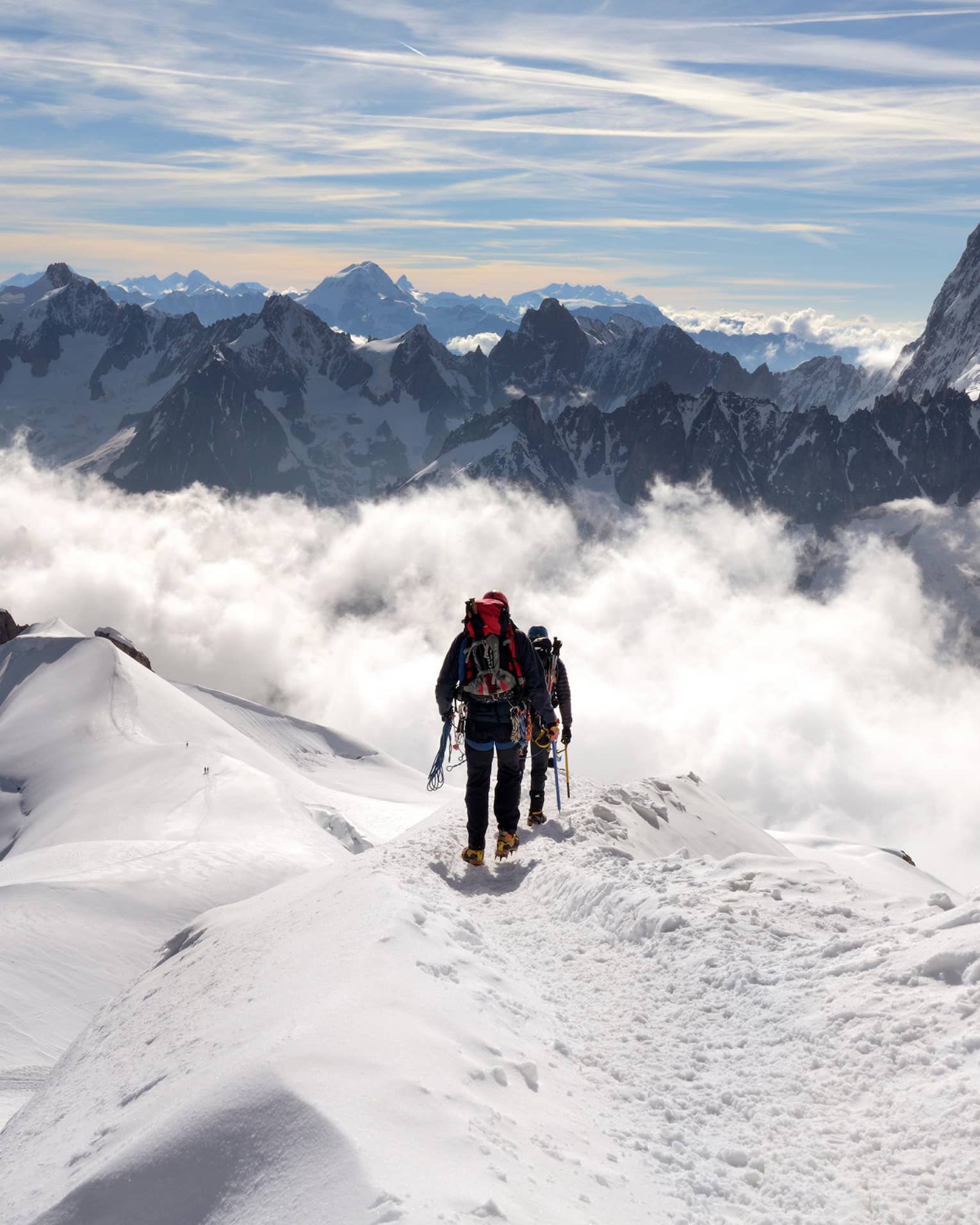Two people hiking at top of icy mountain in French Alps