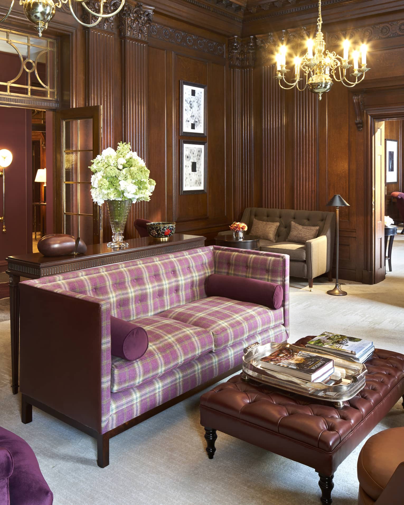 Purple plaid loveseat, velvet and leather armchairs, bench in room with dark wood panel walls