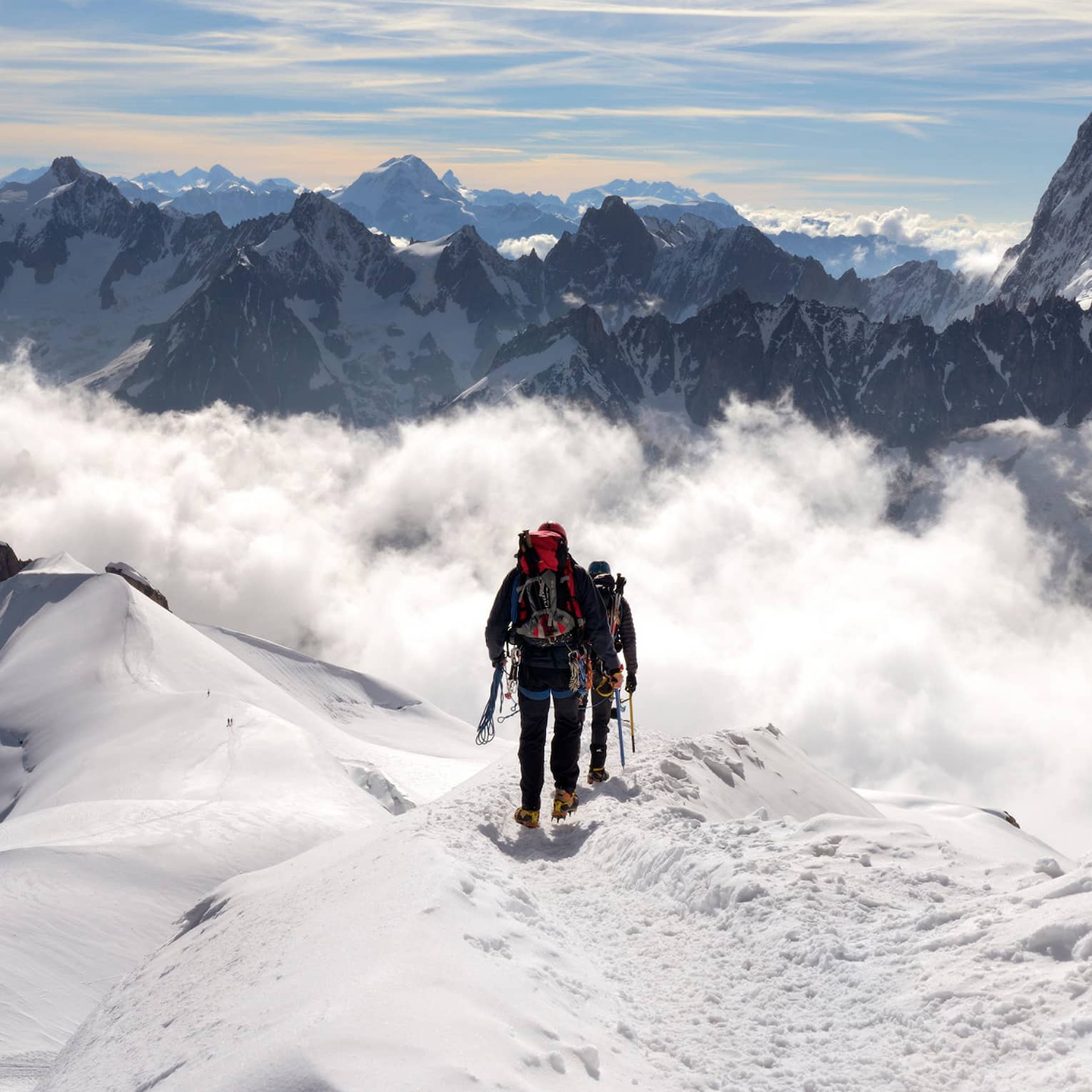 Two people hiking at top of icy mountain in French Alps