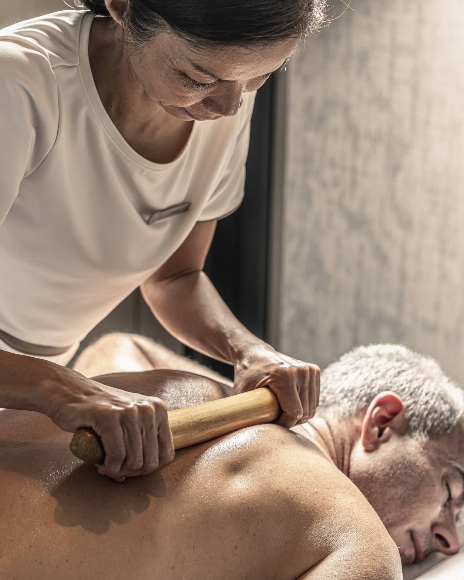 Massage therapist performs a bamboo massage on male guest