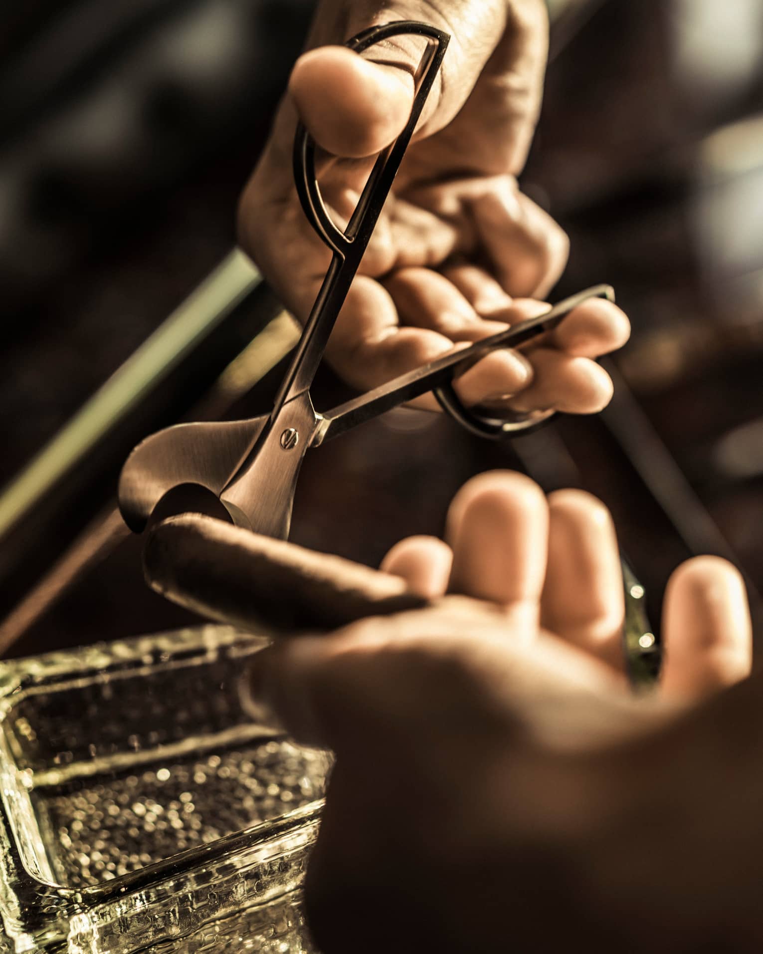 Close-up of cigar cutters clipping end of cigar in dark room