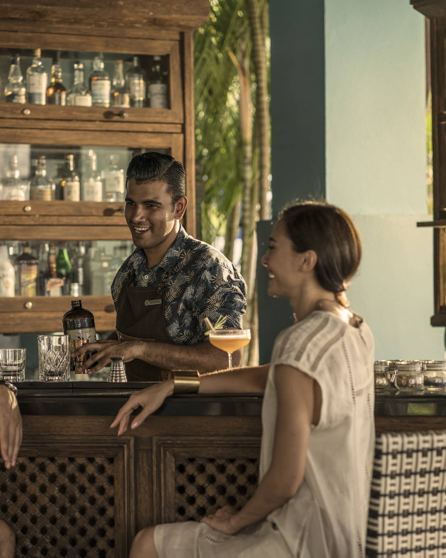Two guests chat with a bartender at rhu bar while he makes a drink