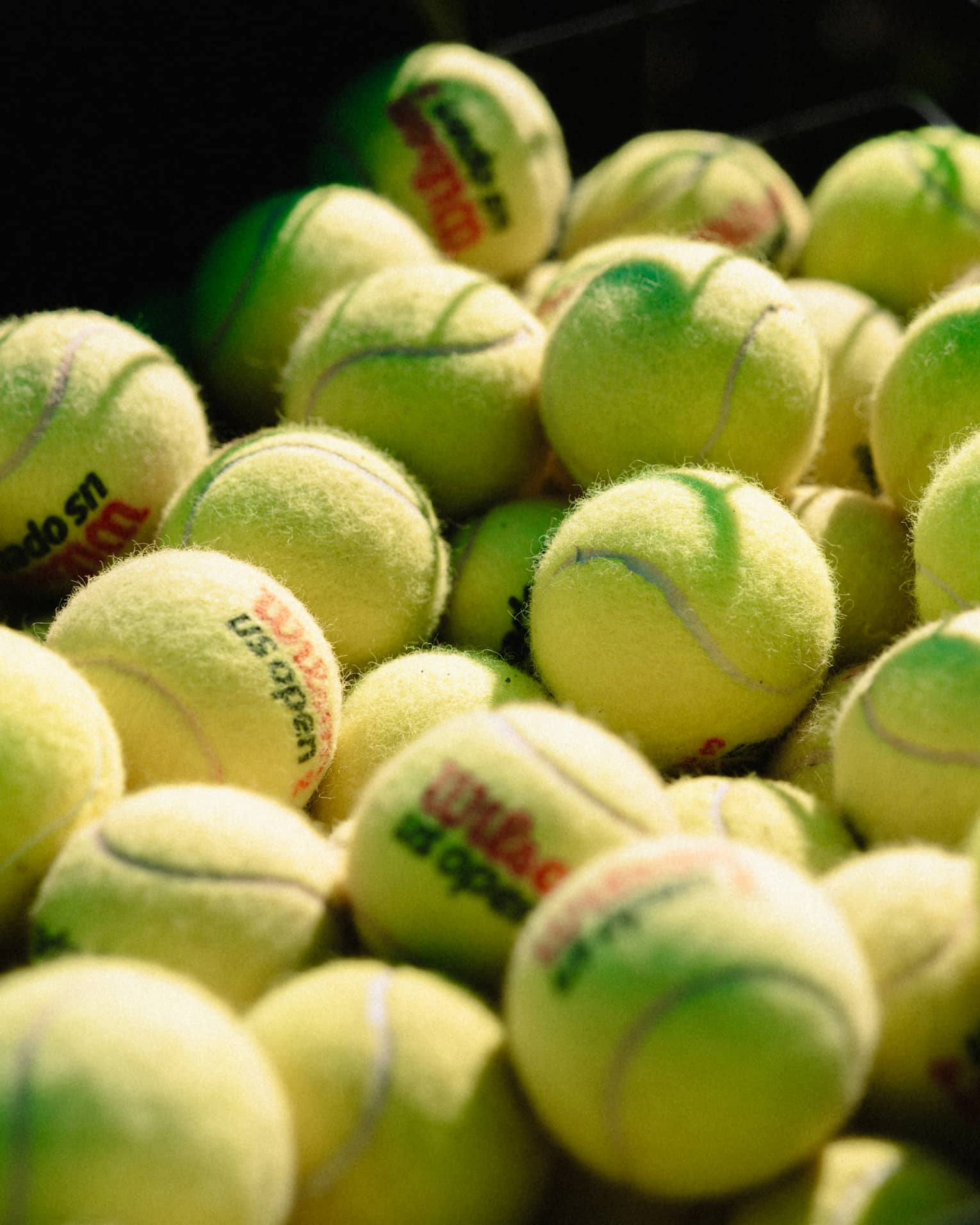 Collection of tennis balls stacked up near a net