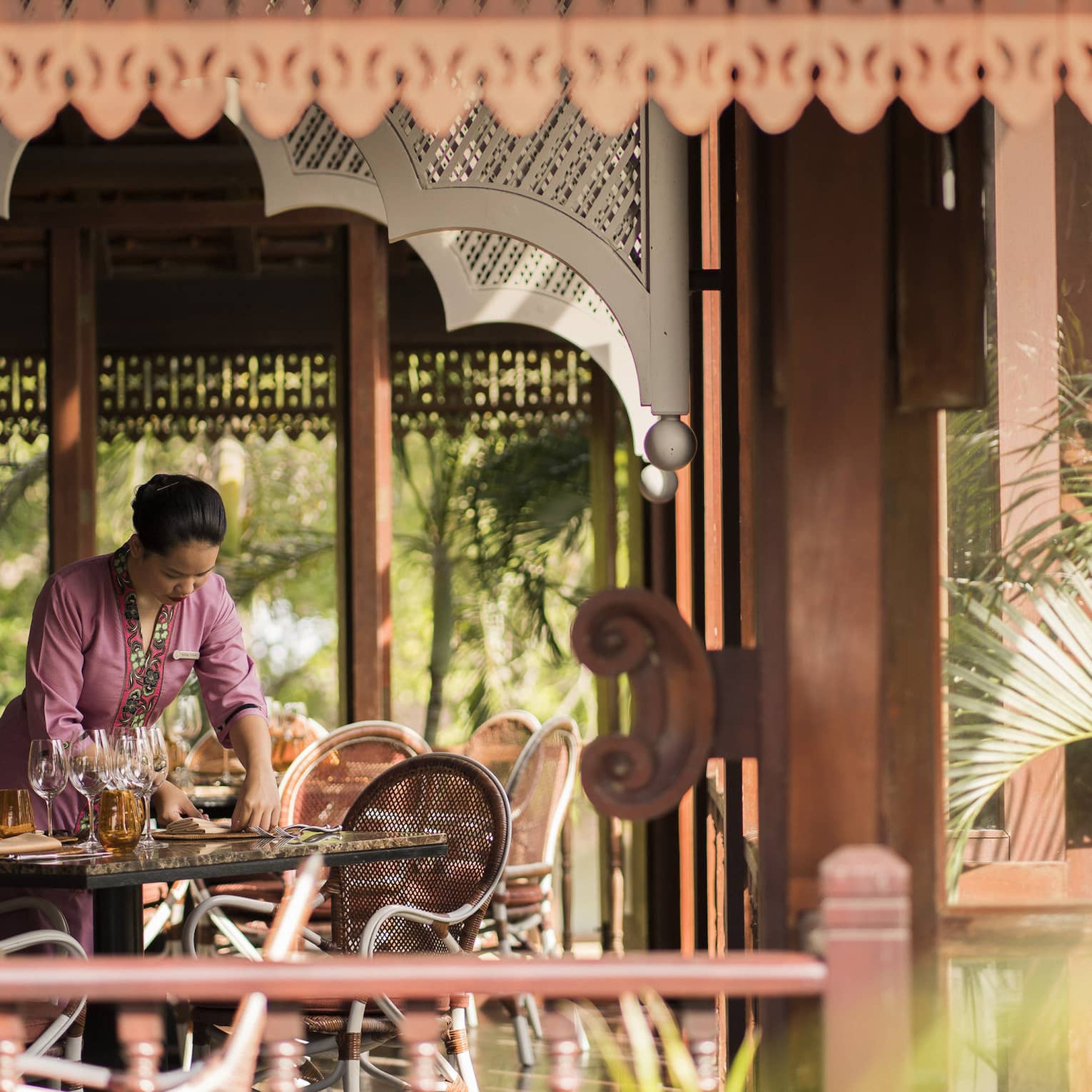A Four Seasons staff setting the table in the open-aired Ikan Ikan at Four Seasons Langkawi