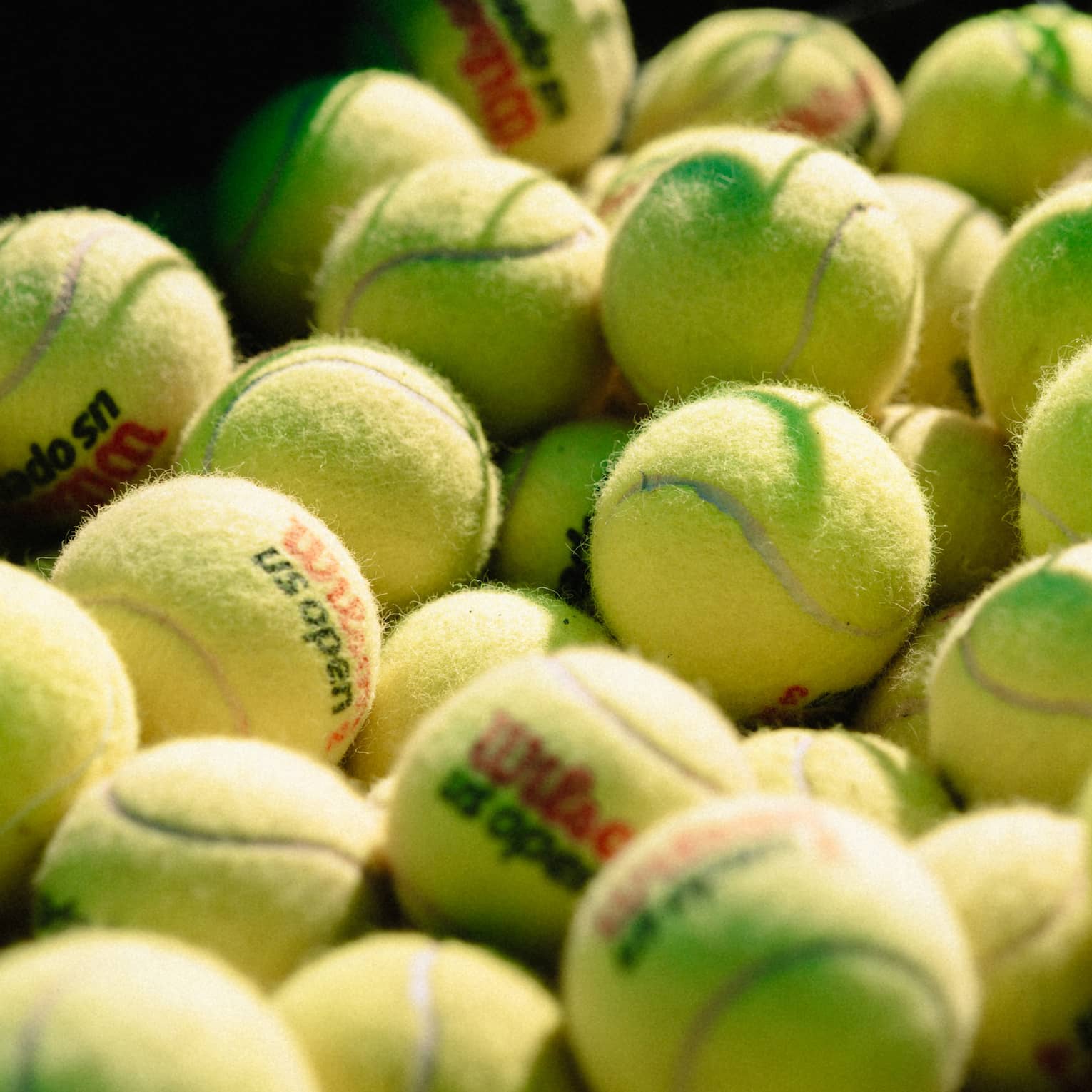 Collection of tennis balls stacked up near a net