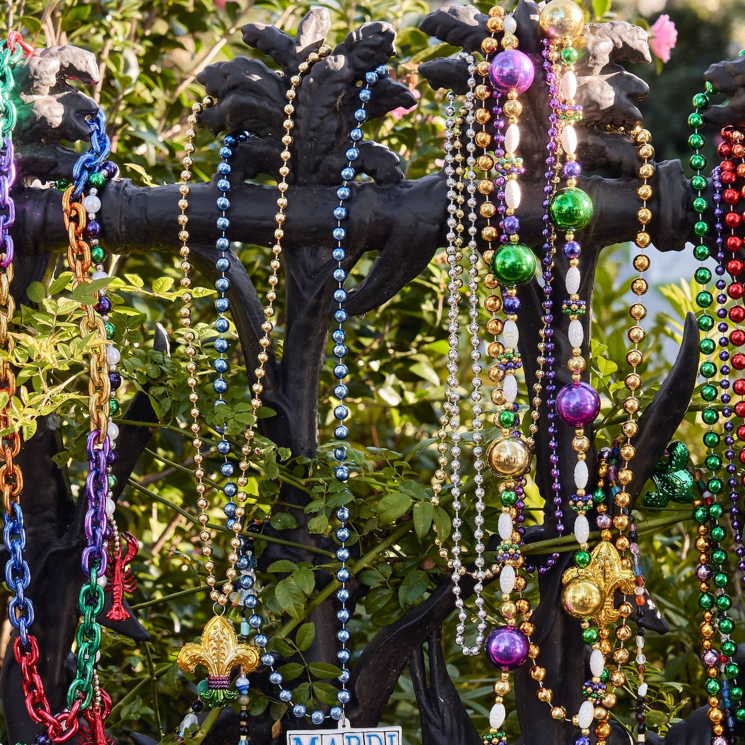 Strands of colourful Mardi Gras beads hanging on a wrought iron post