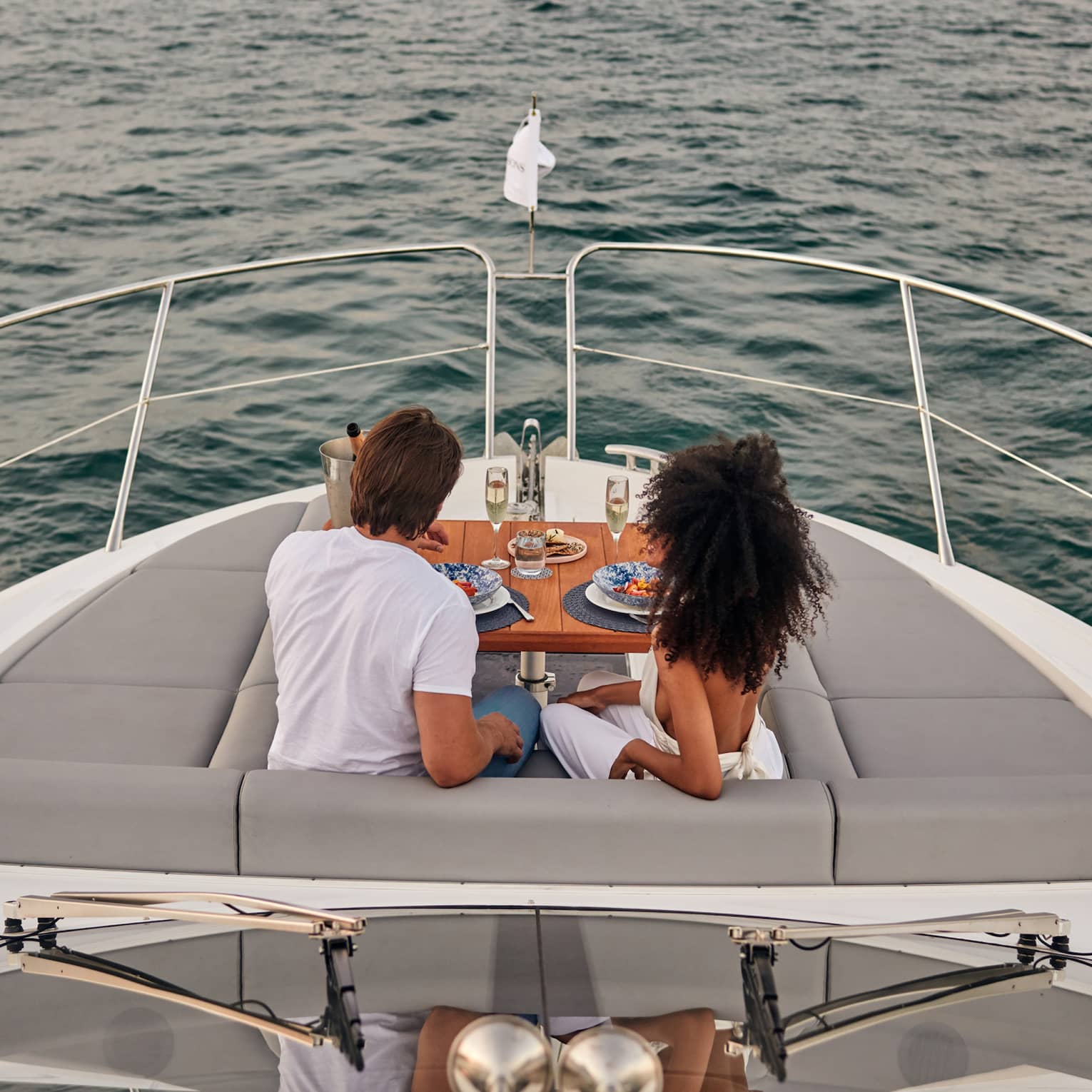 A man and woman eating food on the deck of a boat.