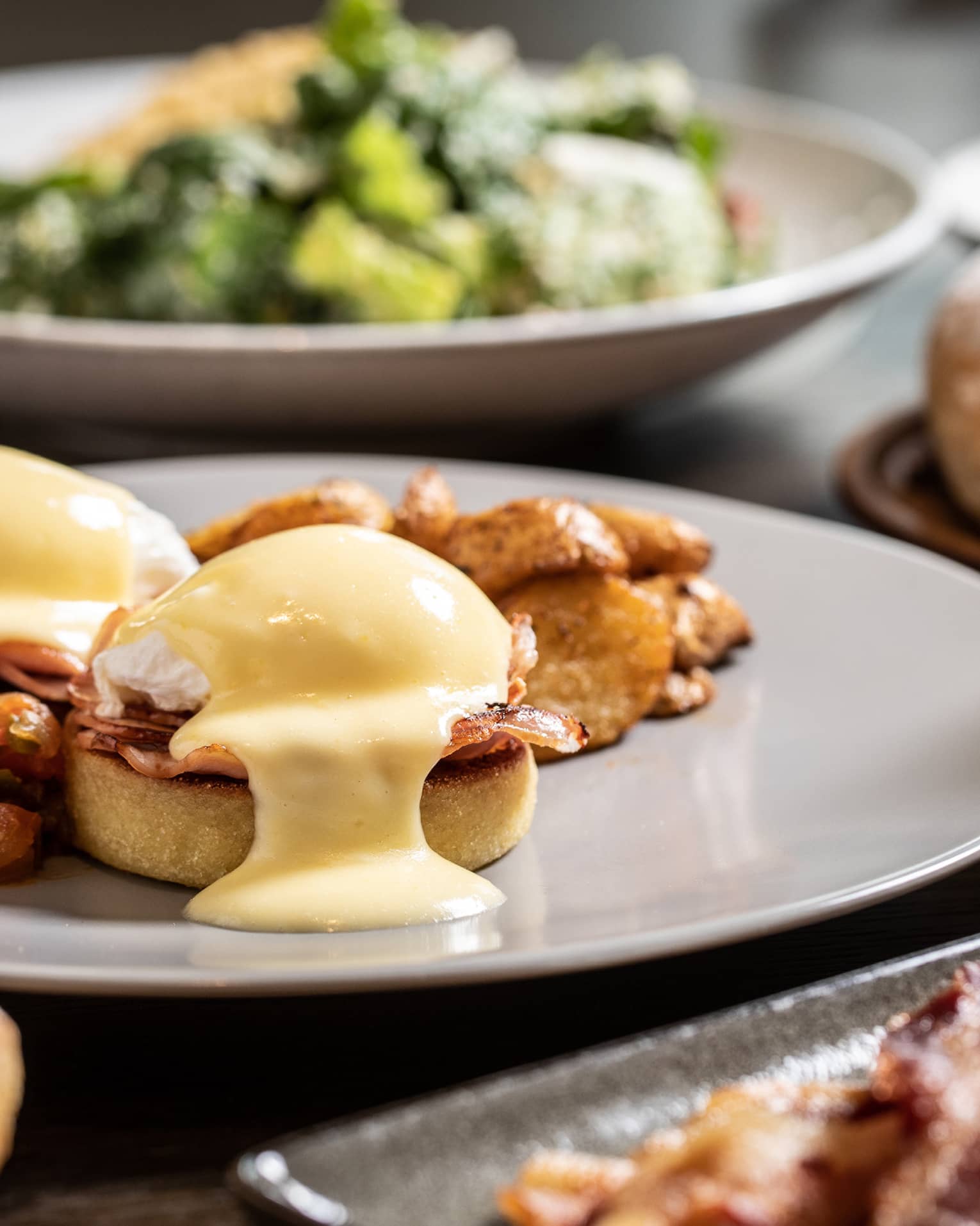 Sunday brunch table with Eggs Benedict, bacon and salad 