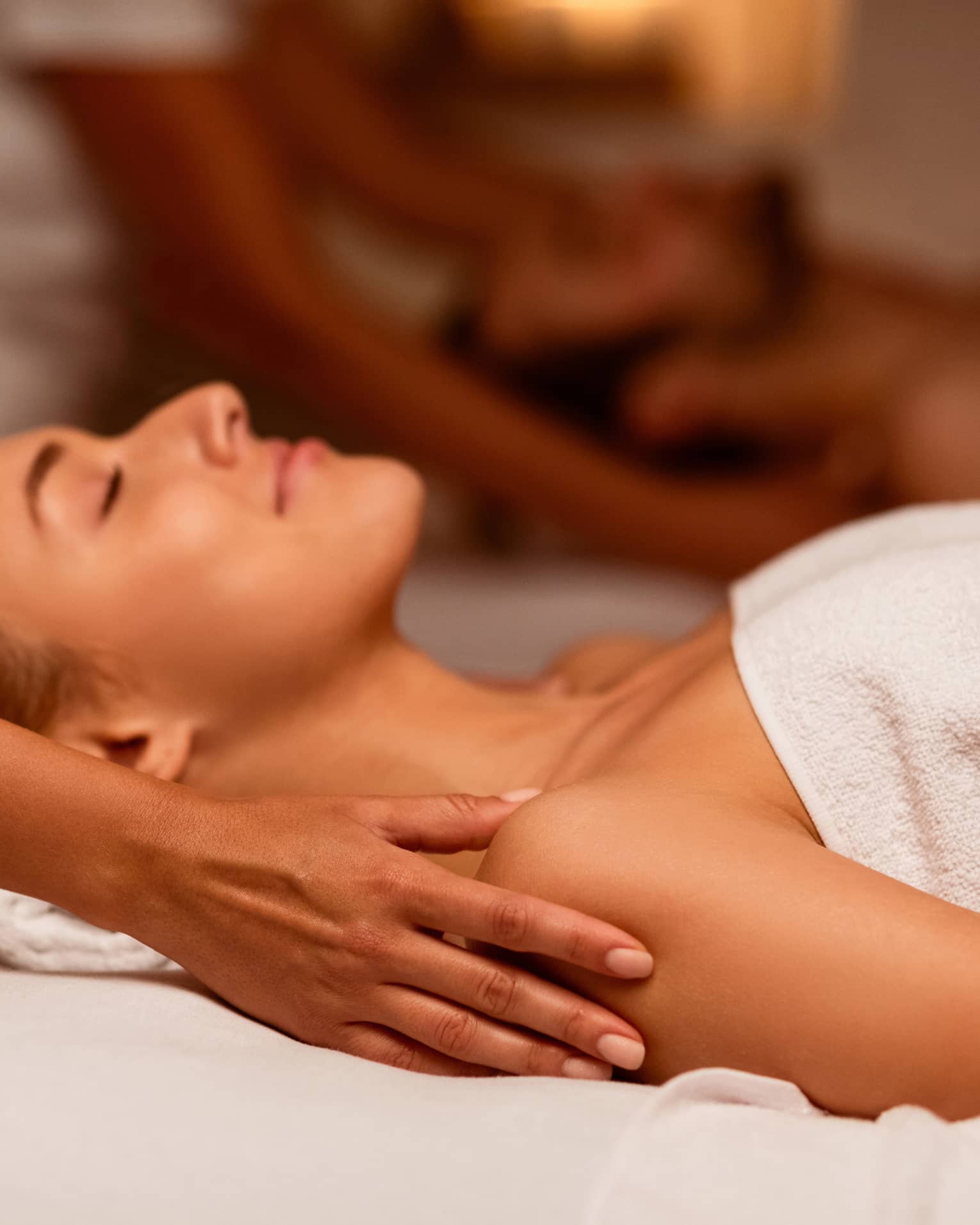 Two spa therapists perform a couples' massage