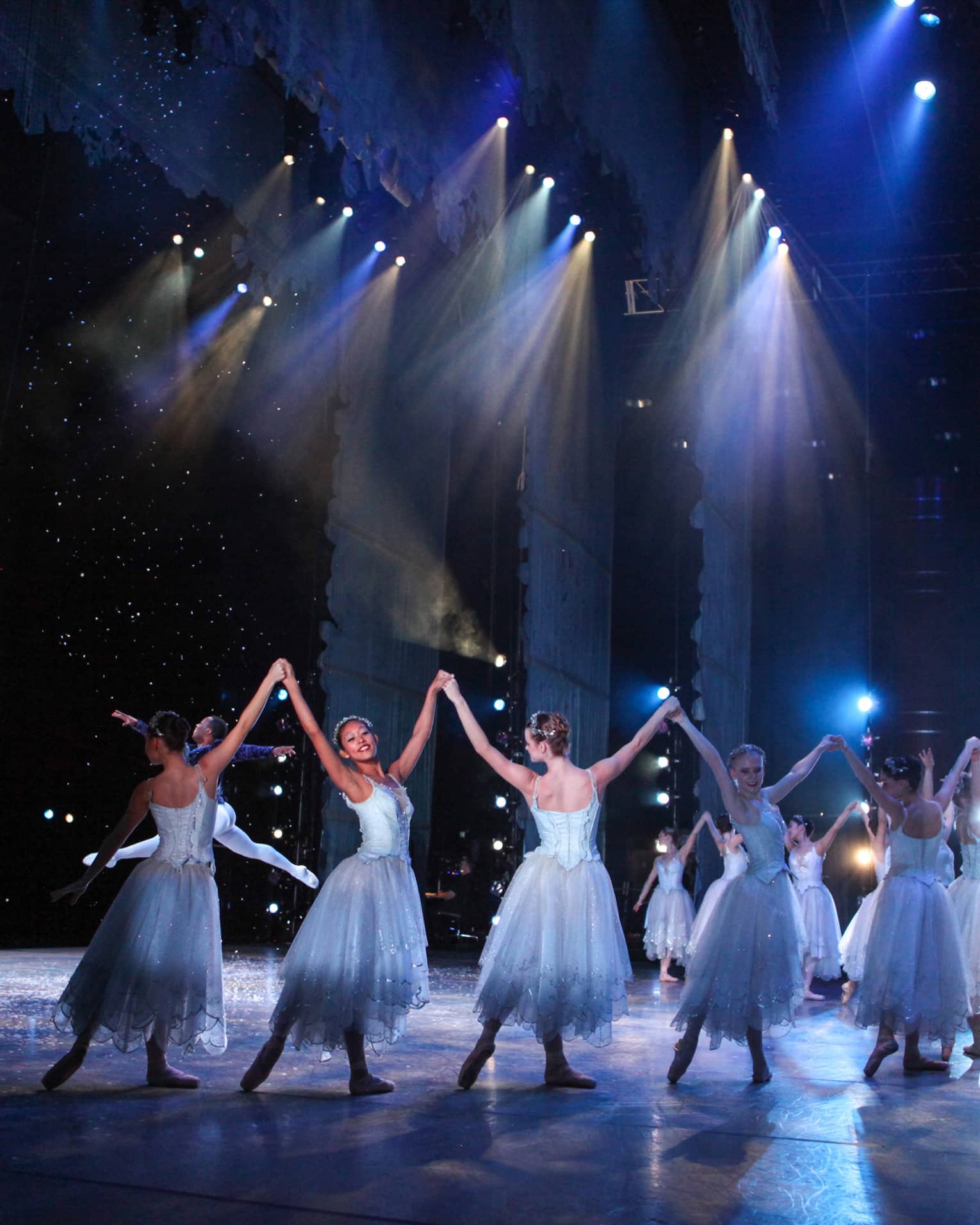 Ballet dancers wearing silvery blue costumes dance on a stage