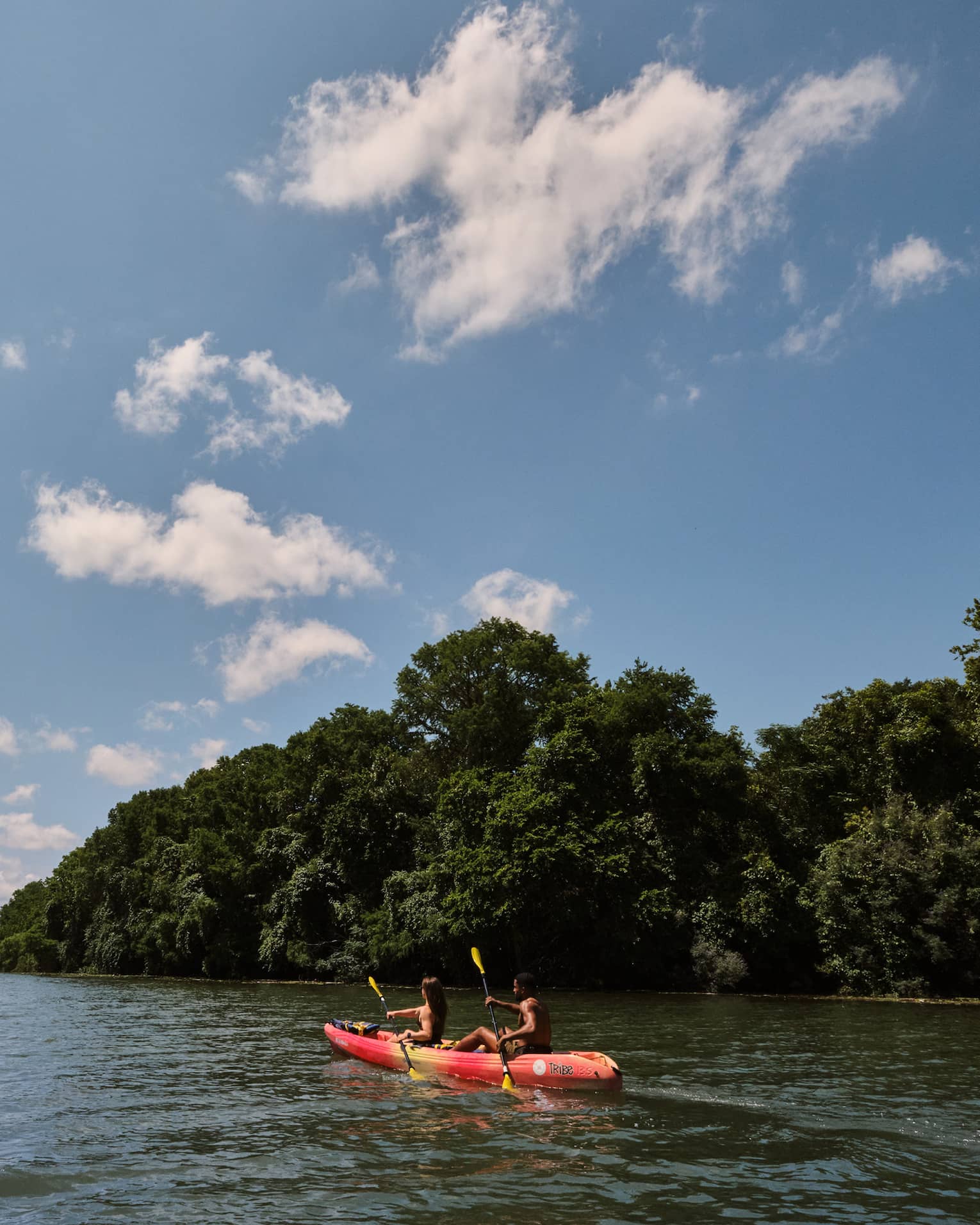 Two guests on a kayak using oars to move the kayak through the water