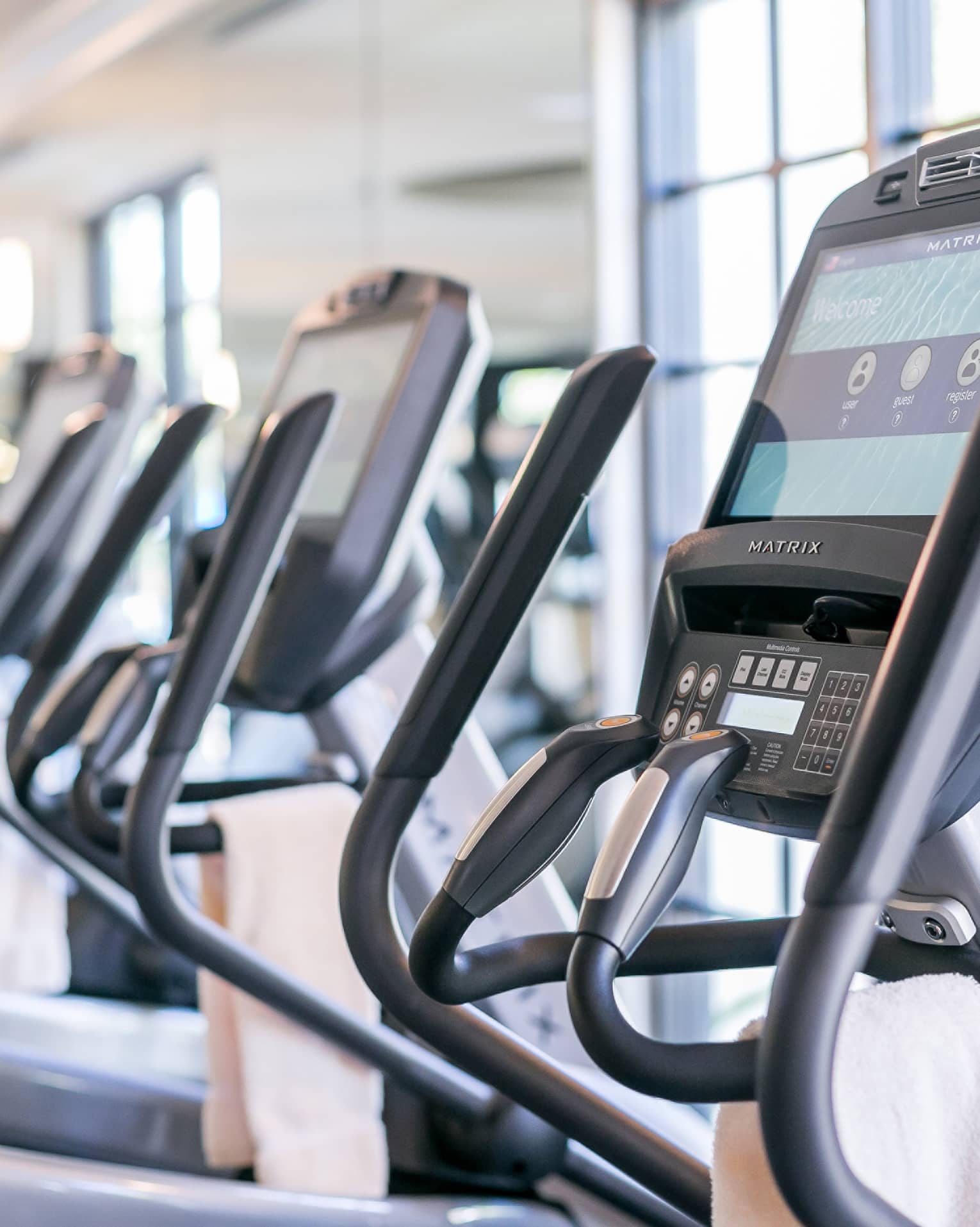 Close-up of cardio elliptical machines in a row in fitness facility