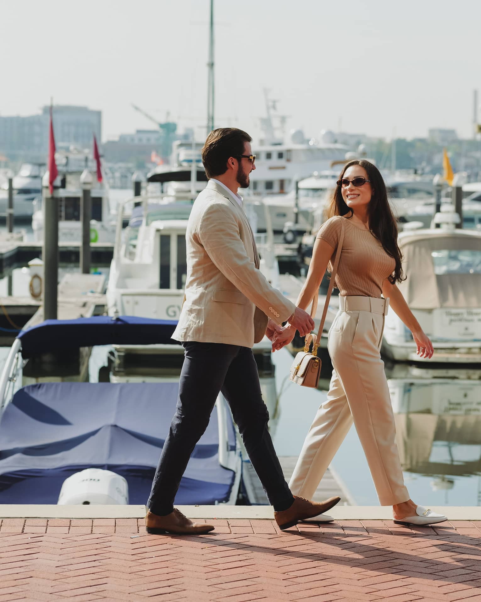 Two guests walking together near a waterfront with boats in the water
