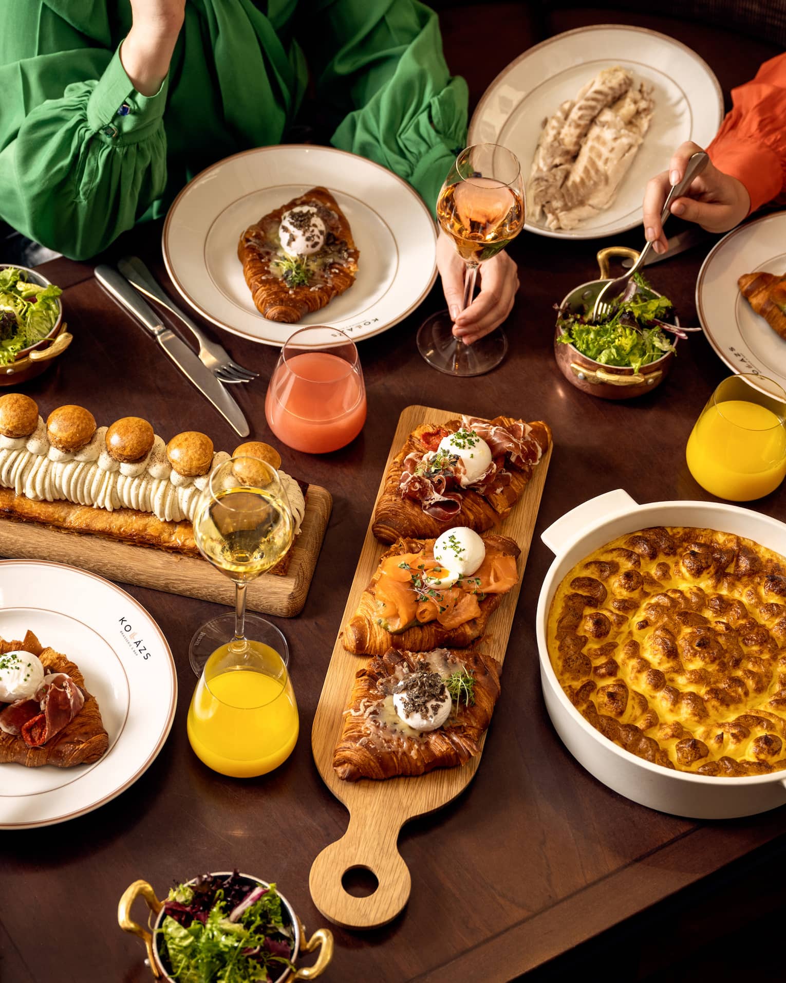 Table filled with assorted gourmet dishes, pastries, salads, and drinks during a shared meal