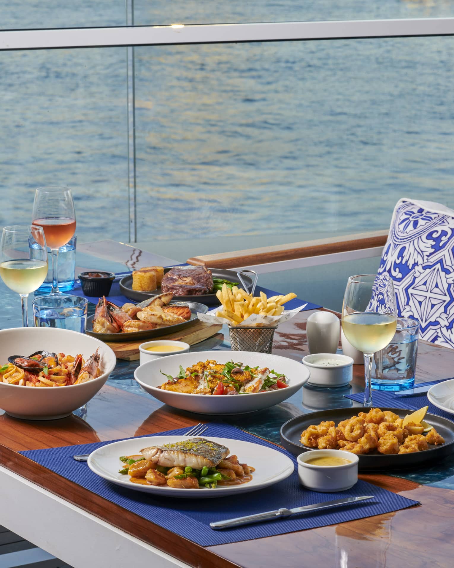 A spread of colourful seafood selections with wine, furniture in a white and blue colour palette, overlooking the Nile.
