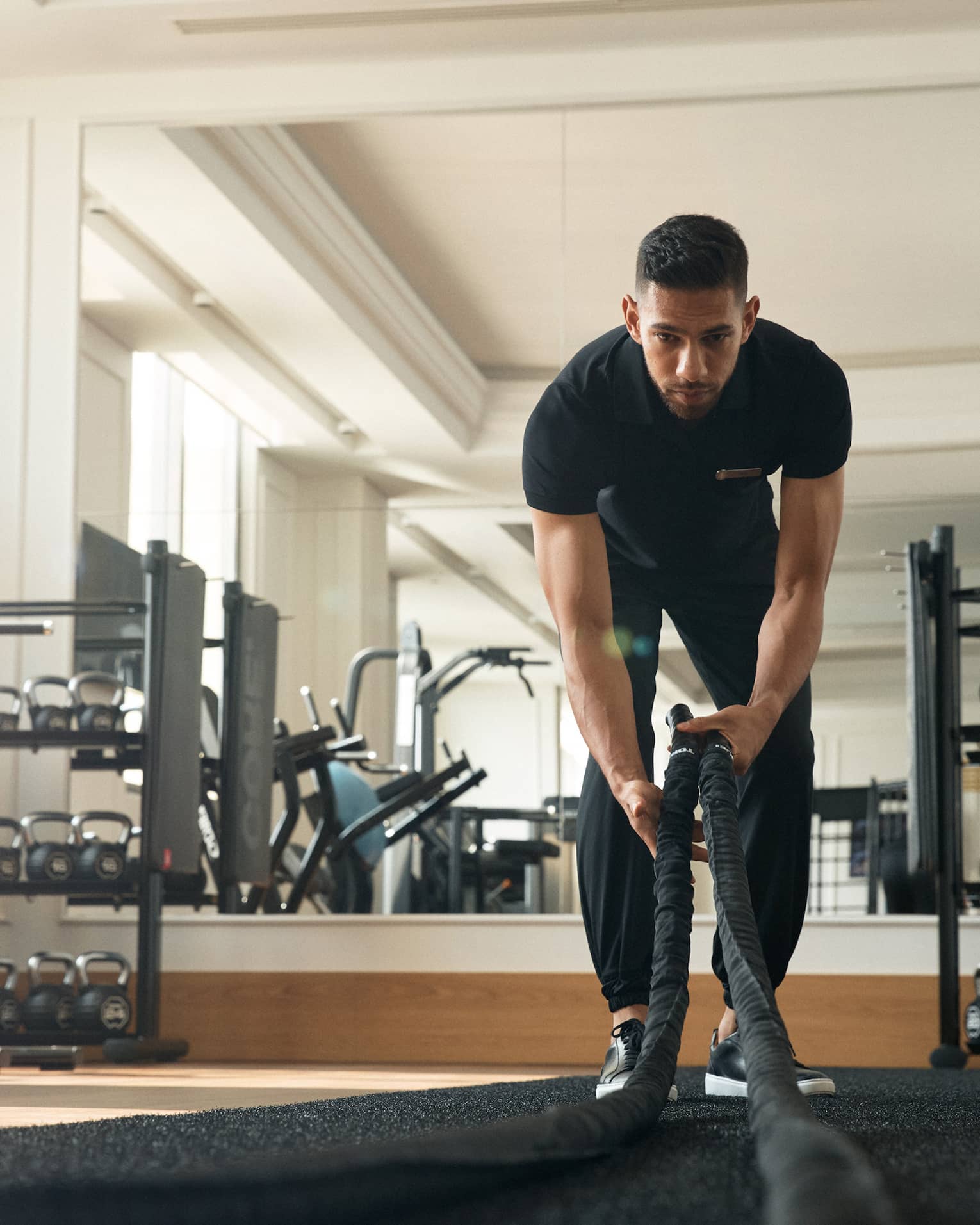 Man works out in fitness room using a heavy rope