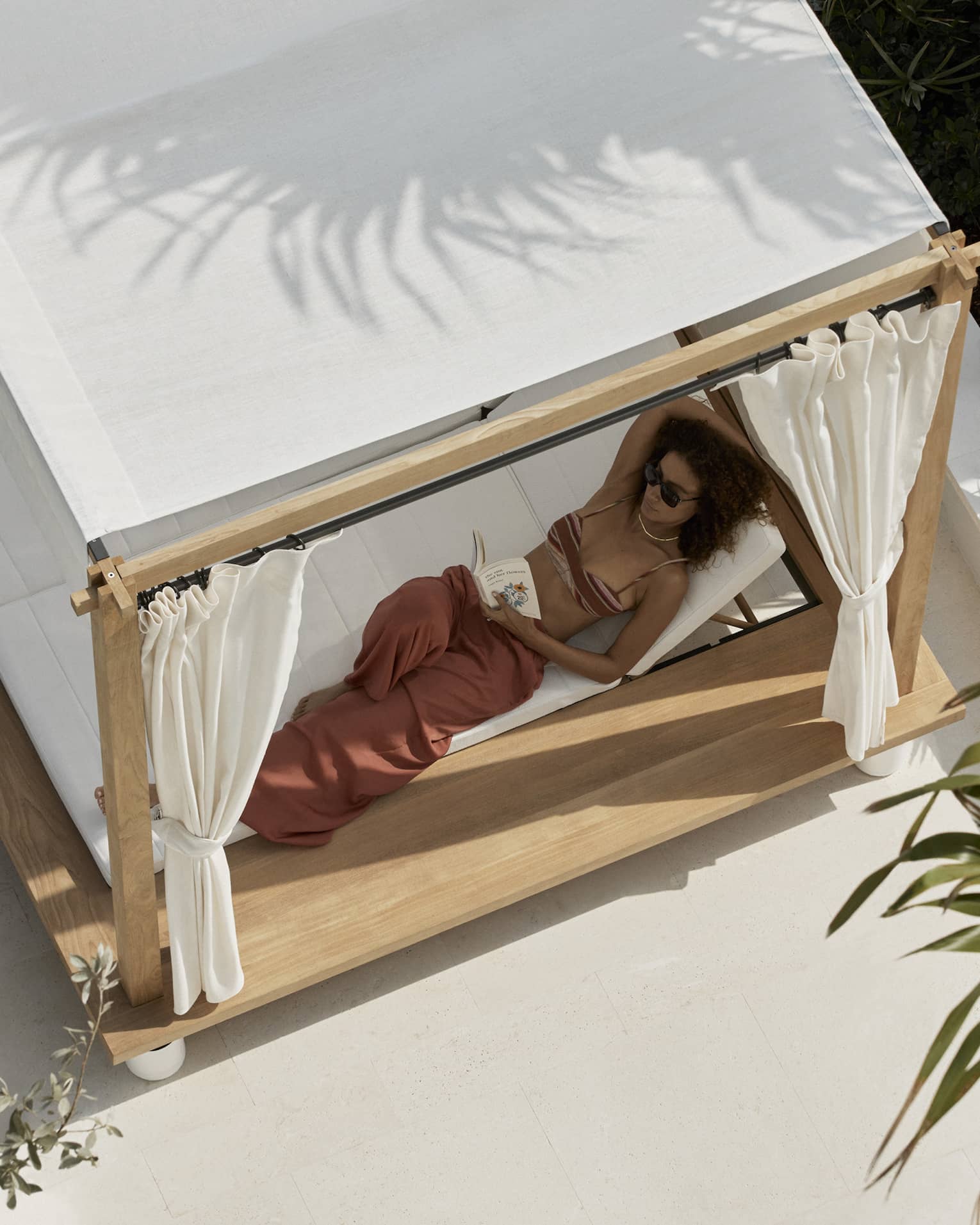 Aerial view of woman lounging in a covered poolside daybed