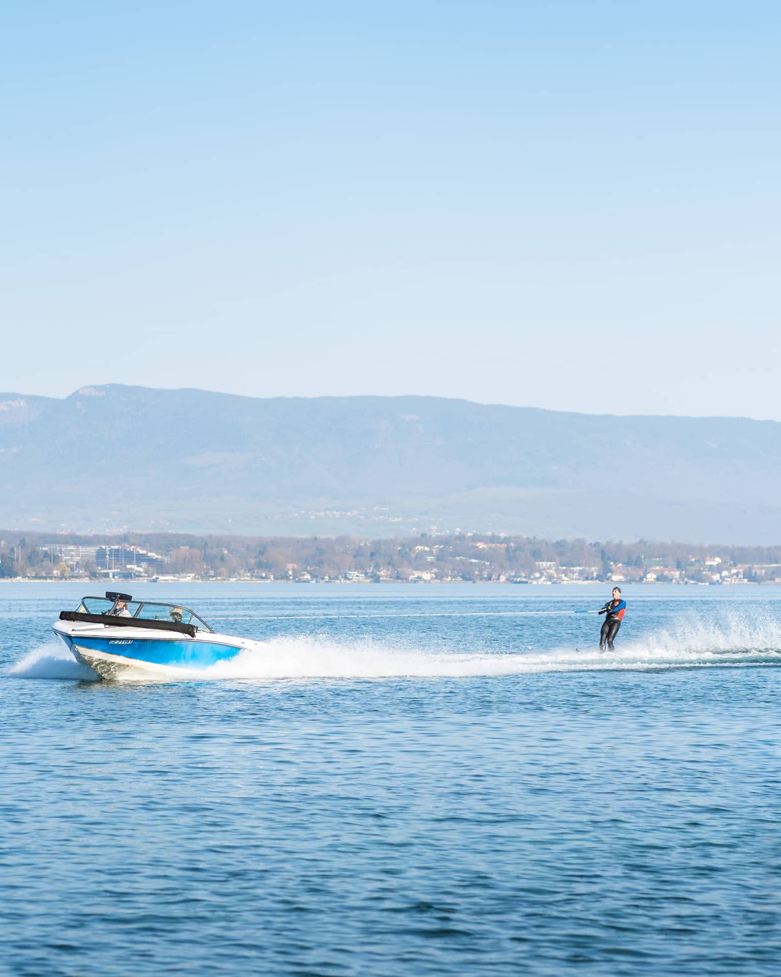 Blue-and-white boat pulling waterskiier on Lake Geneva