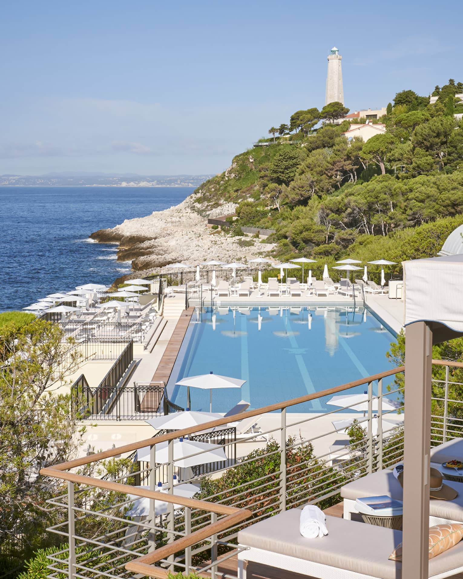 View from terrace of Club Dauphin pool, Mediterranean, green hillside and lighthouse