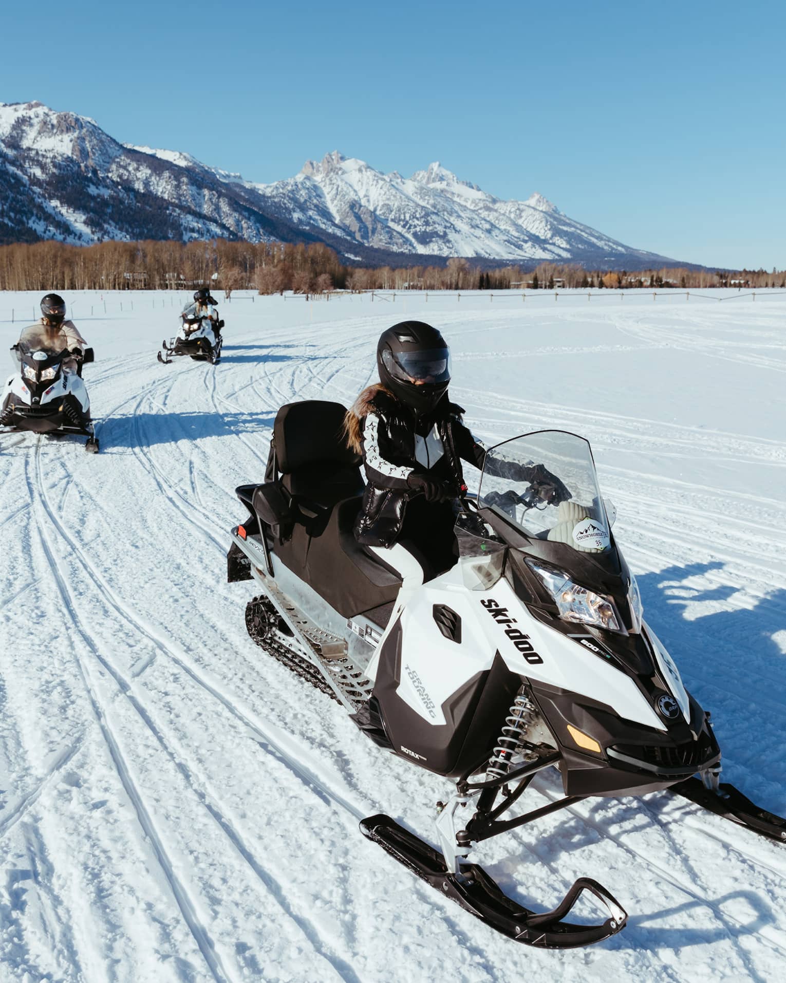 Three people on snowbmobiles.