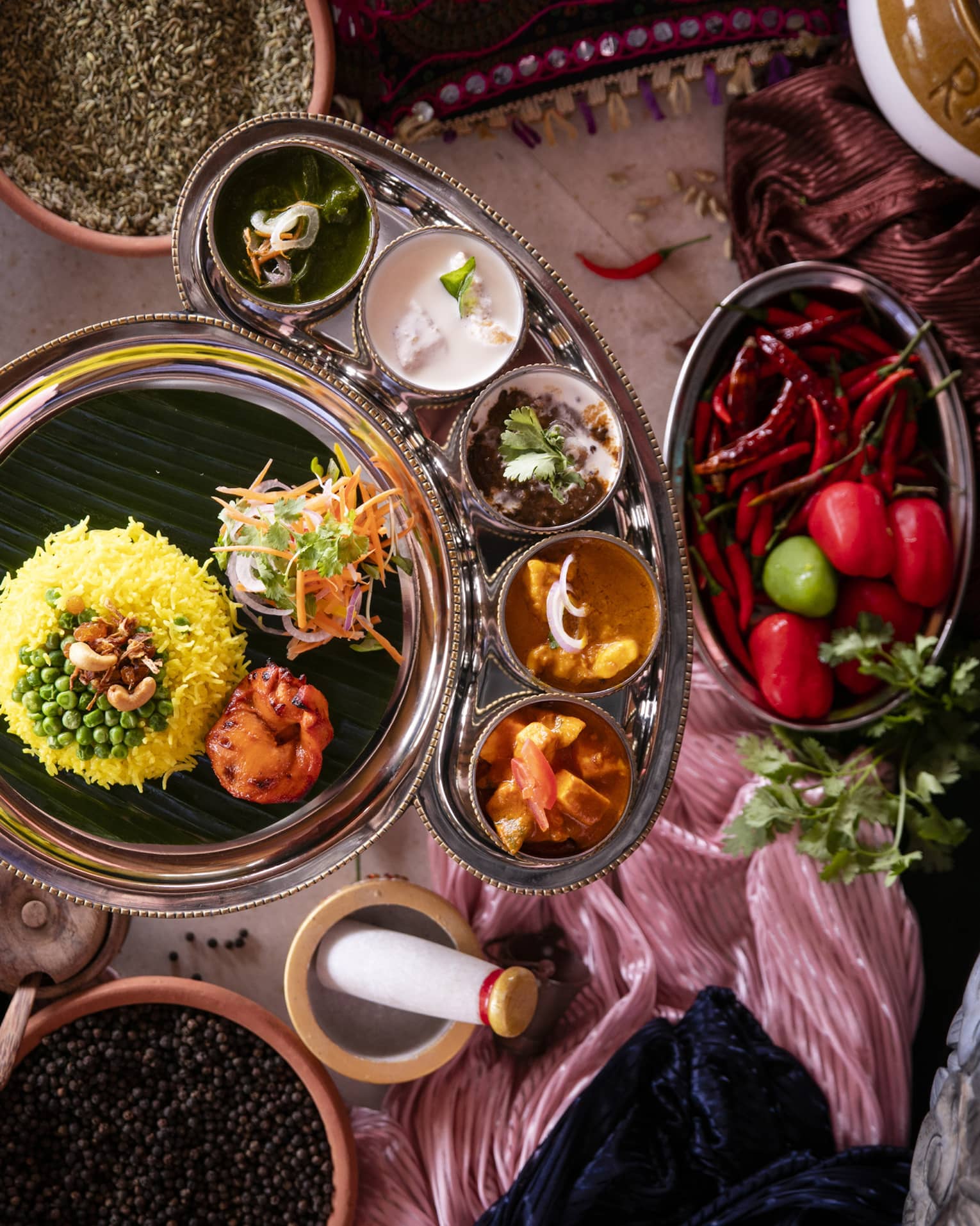 Aerial view of curry dish with rice, bowls of condiments and mortar and pestle