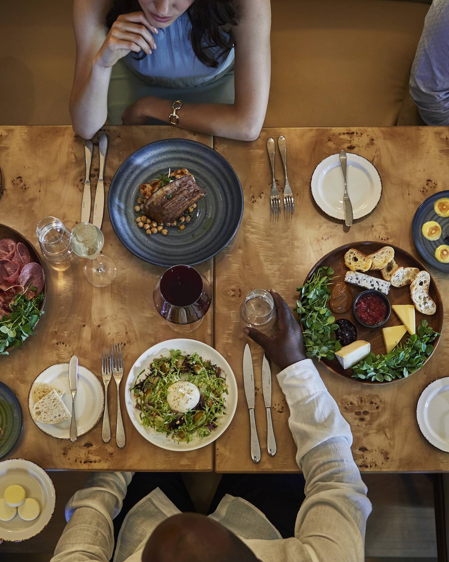 Aerial view of a group dining at a wooden table topped with various vibrant culinary dishes