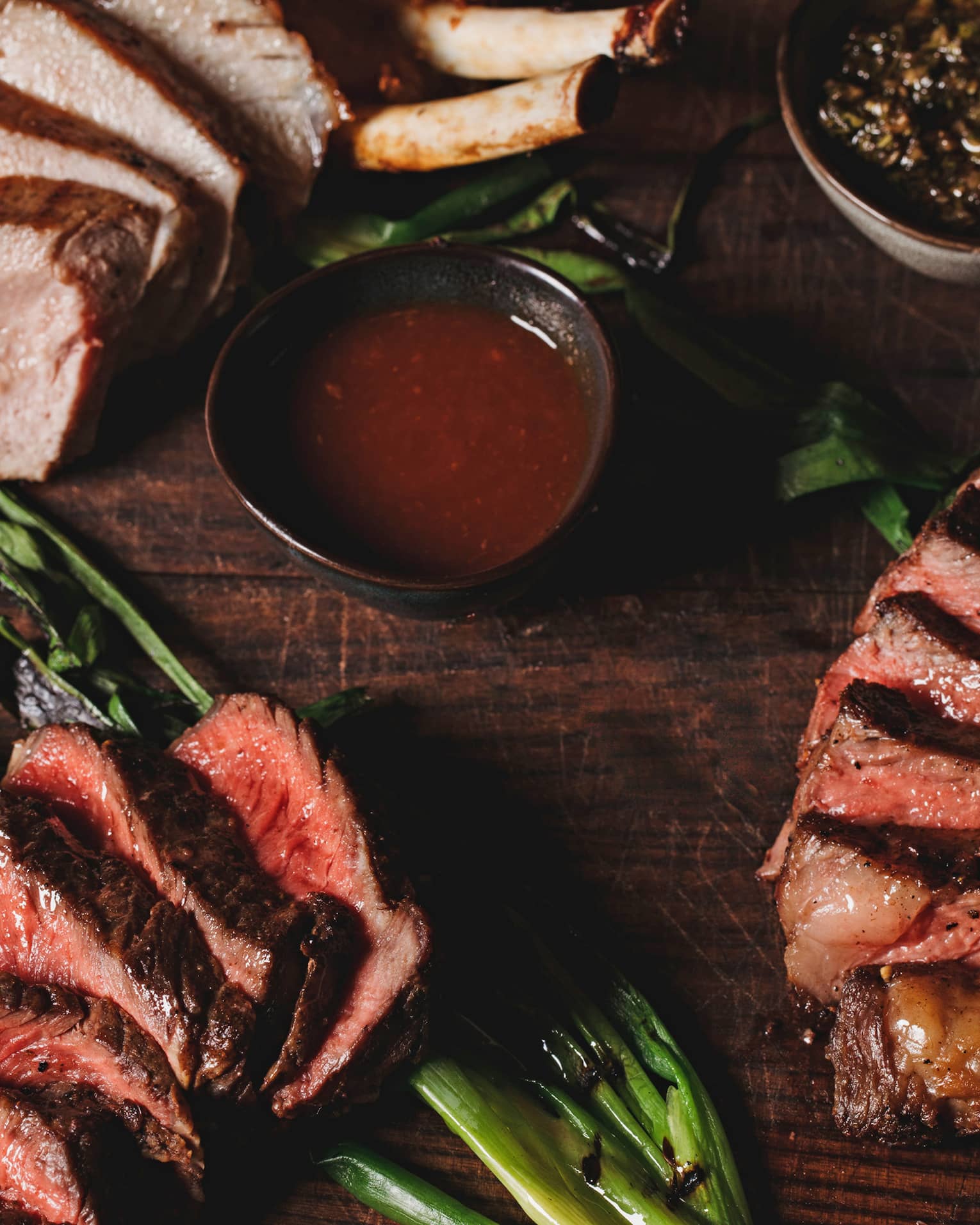 A aerial view of the La Hiki Steak over green onions with a red sauce on the side