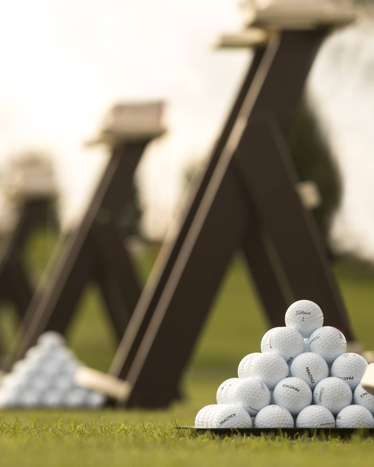 Stacks of white golf balls on lawn in front of wood panels