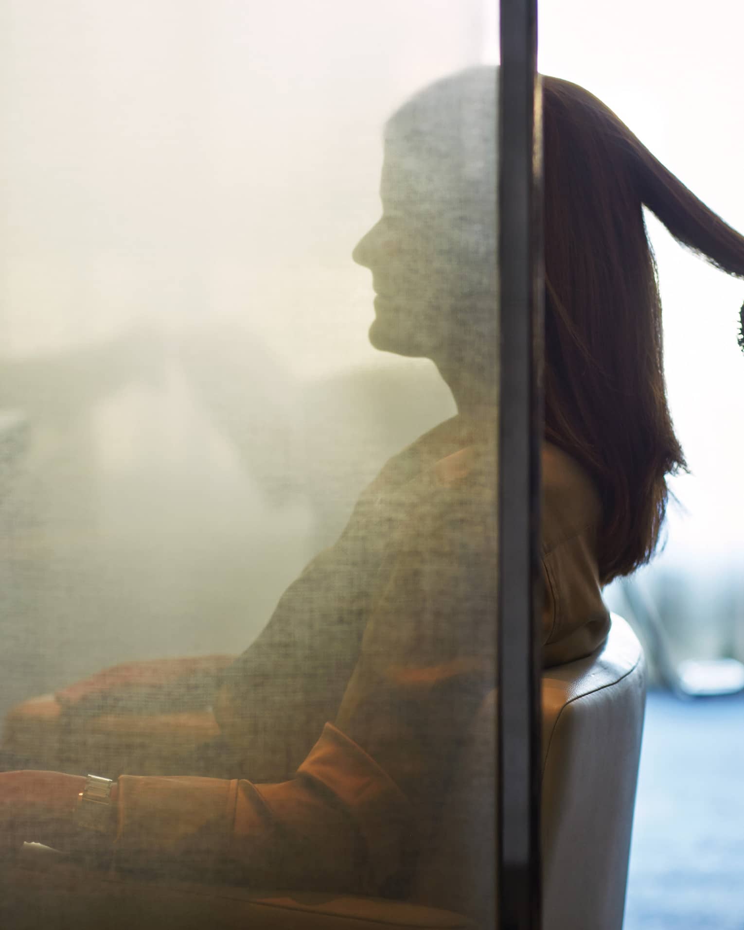 Silhouette of woman behind salon screen as hairdressers brushes, blow dries hair